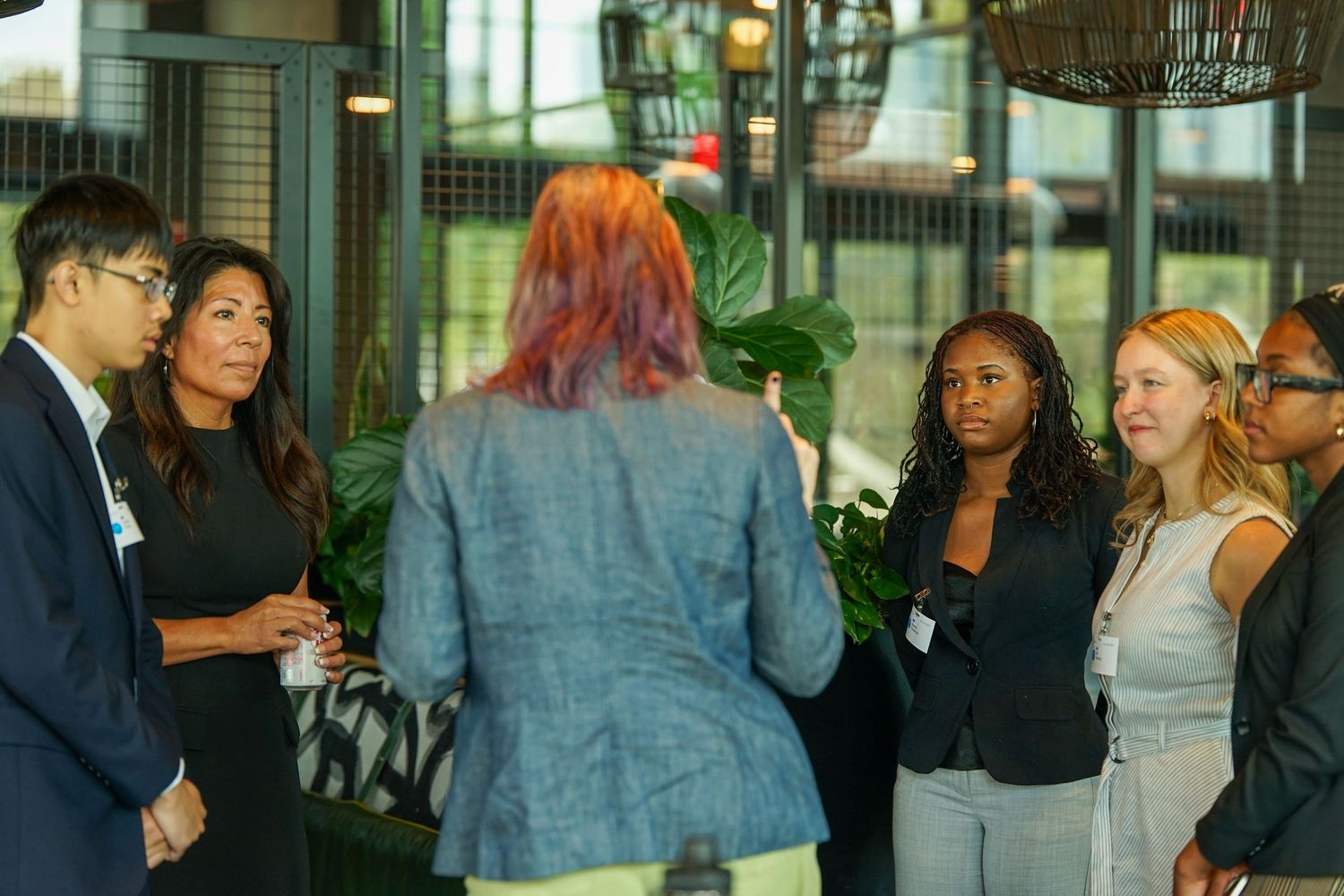 Diverse group of professionals networking in a modern indoor space with plants.