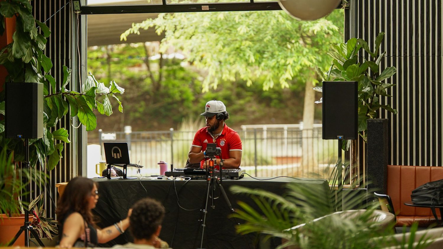Outdoor event space with vertical striped walls and tropical plants creating an atmospheric setting.