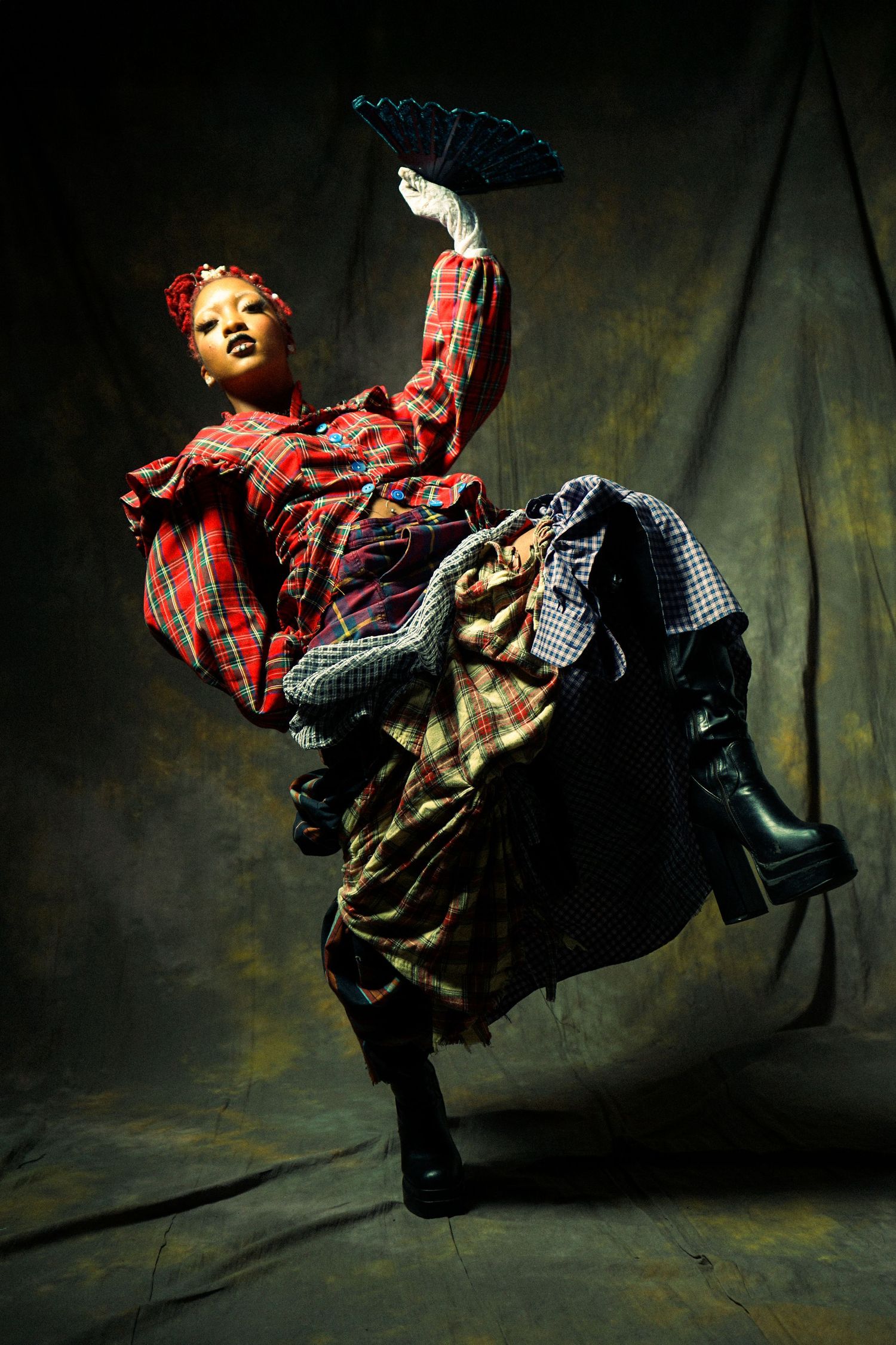 A sequence of dynamic dance movements captured in low light showing a figure in plaid and dark clothing spinning through space.
