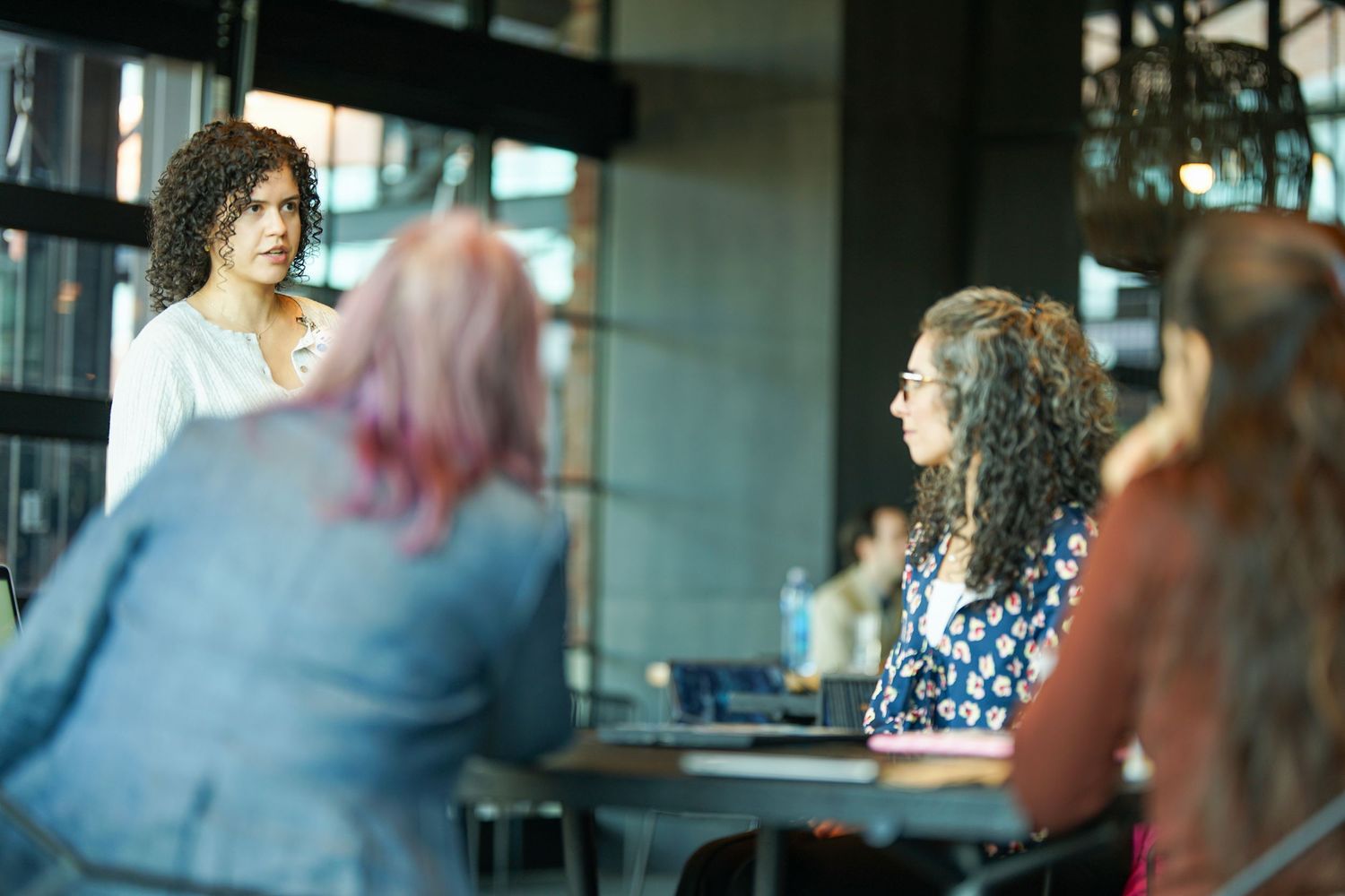 Women engaged in a professional discussion at a modern office meeting table in a collaborative workspace.