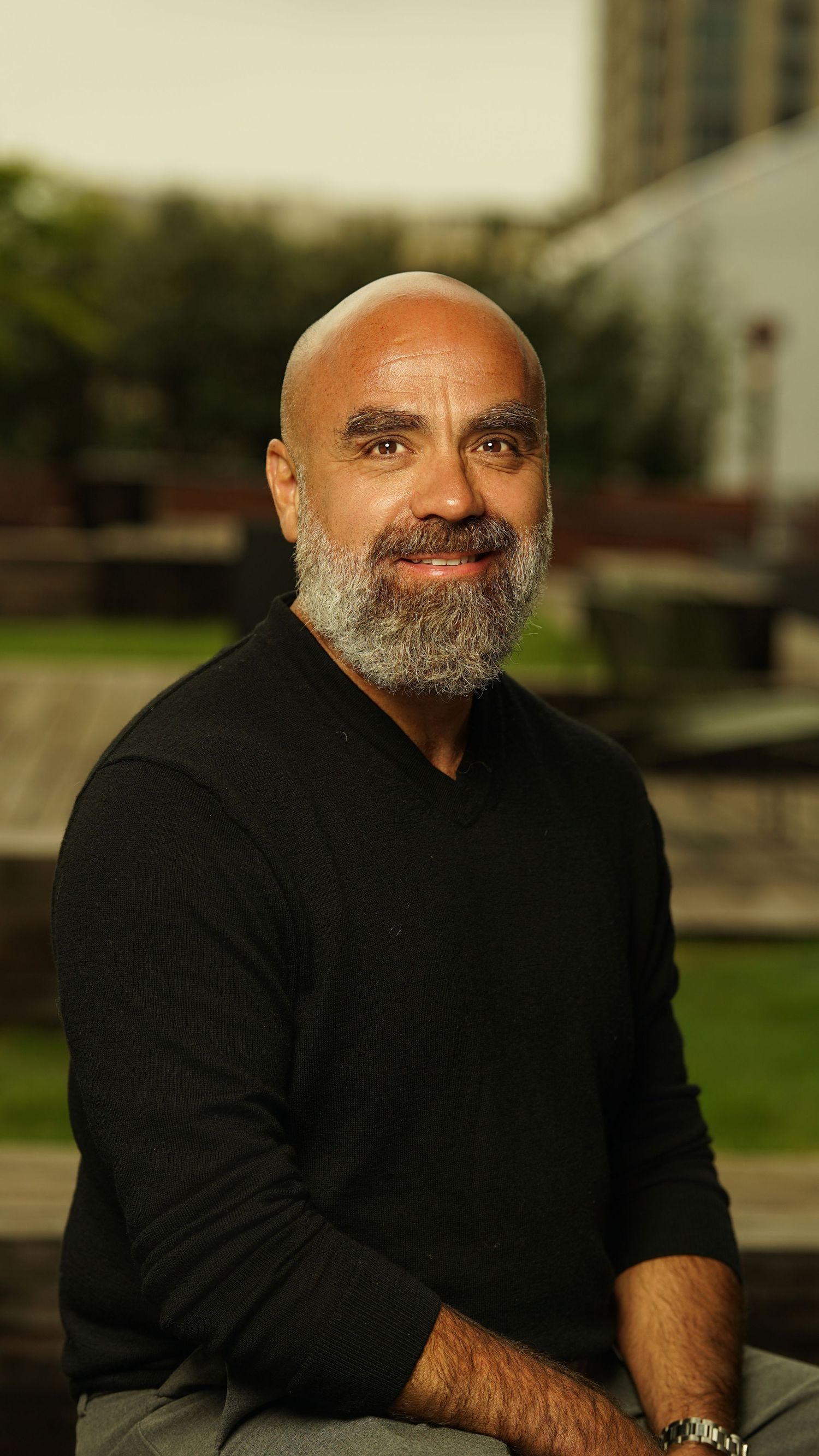 Portrait of a person with a beard wearing a black shirt against a soft-focus background.