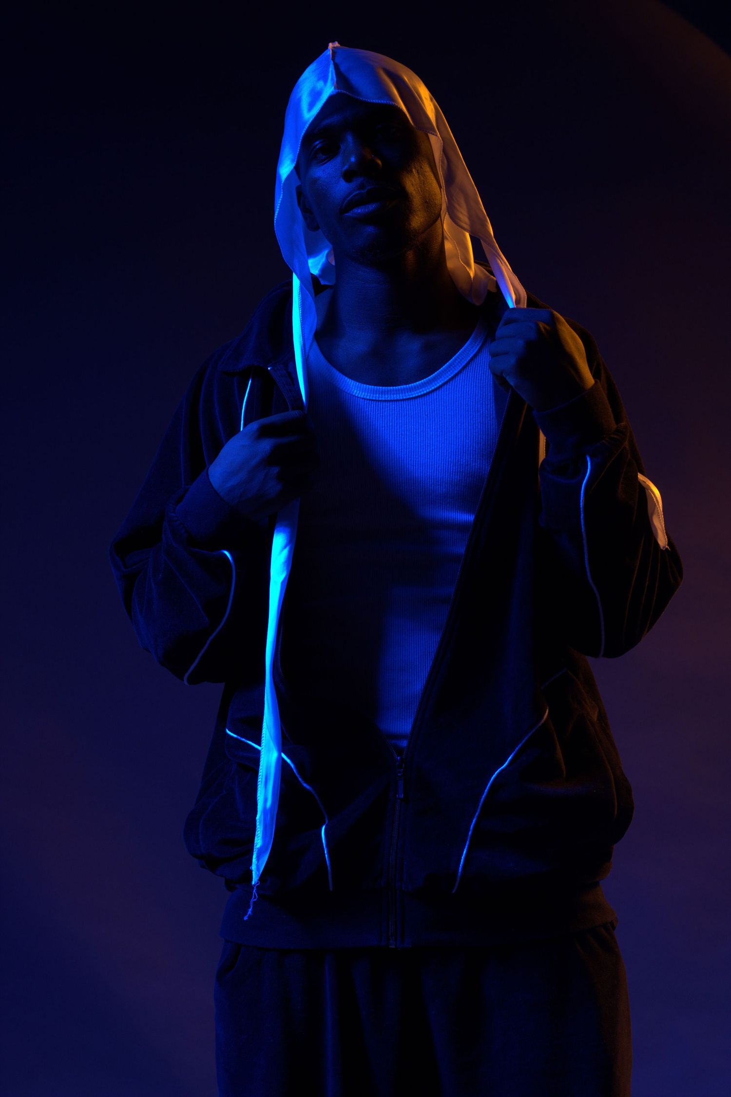 Moody portrait with blue neon lighting creating atmospheric urban nighttime aesthetic.