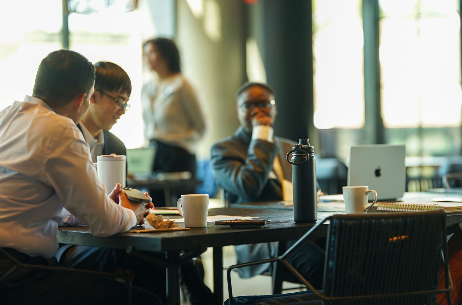 Diverse professionals having a business meeting at a cafe table with laptops and coffee cups.