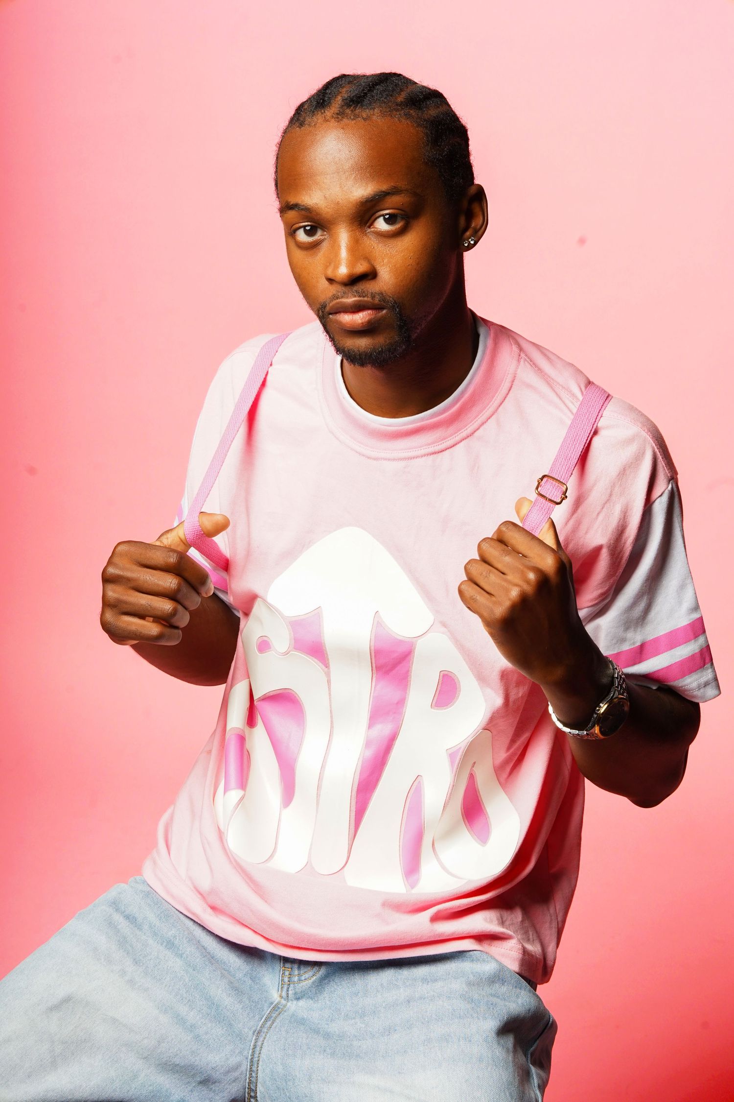 Model in pink and white athletic shirt poses against pink background showing thumbs up gesture.