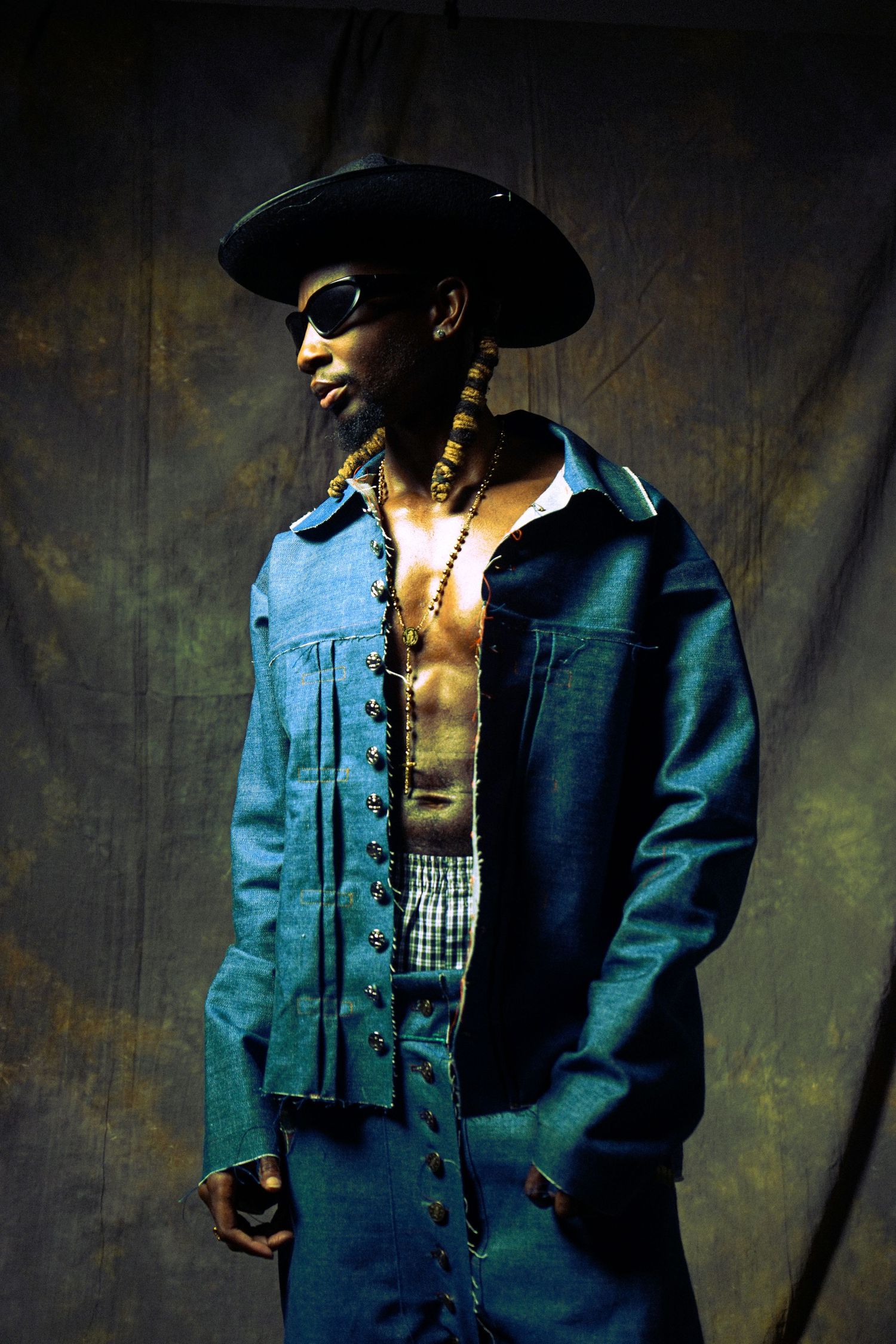 Artistic portrait series showing a person in denim jacket and black hat against dark textured background.