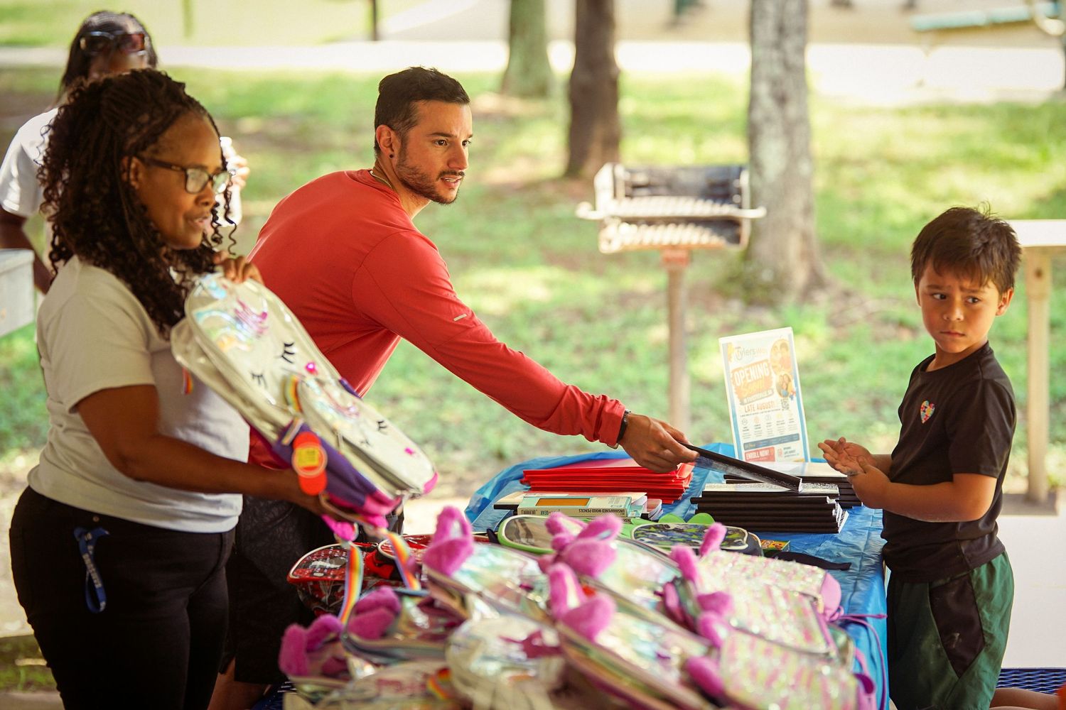 Adults distribute school supplies to child at Tyler's Way Foundation outdoor community event.
