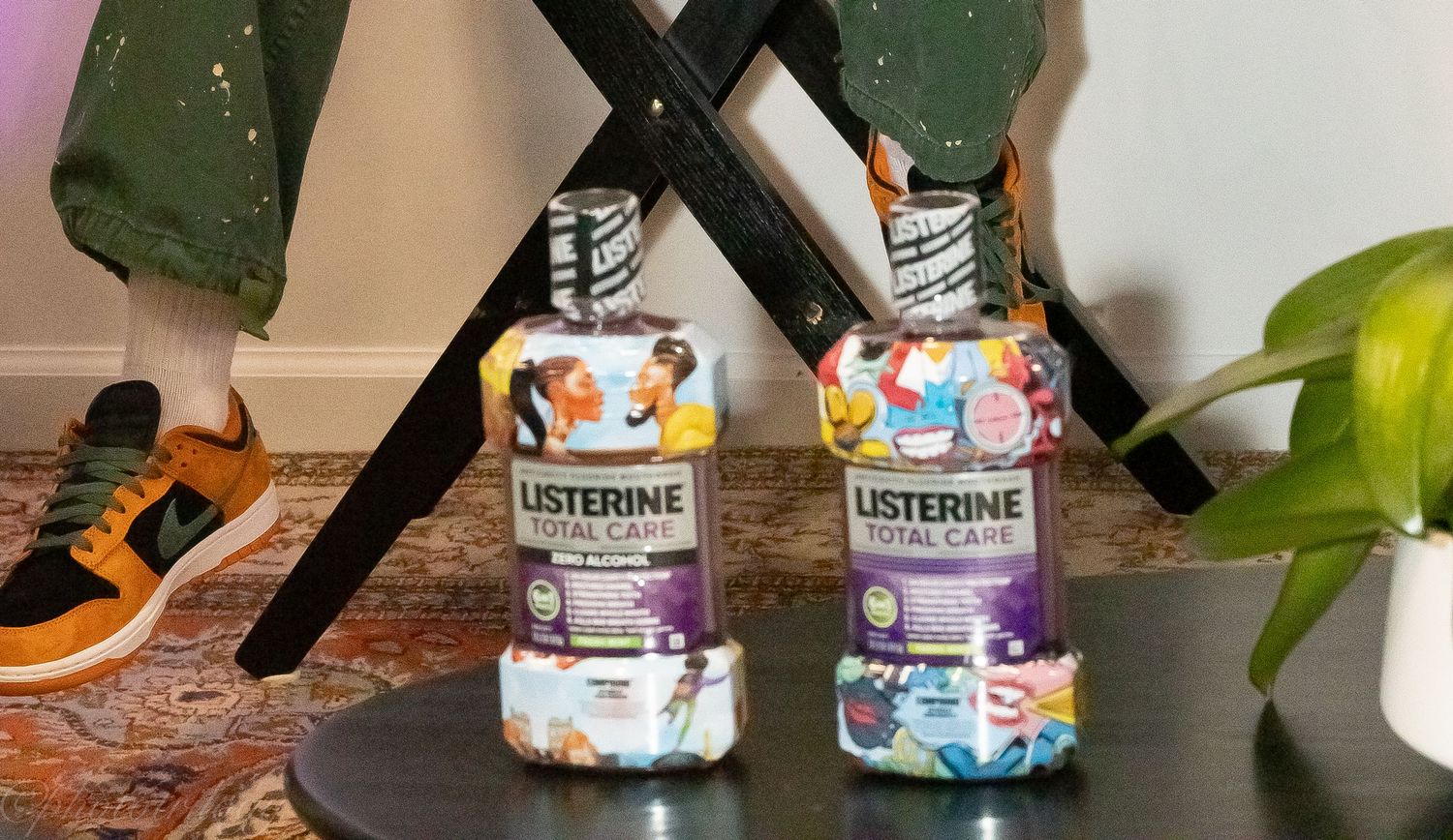 Two Listerine Total Care mouthwash bottles with colorful artistic labels displayed on a dark table indoors.