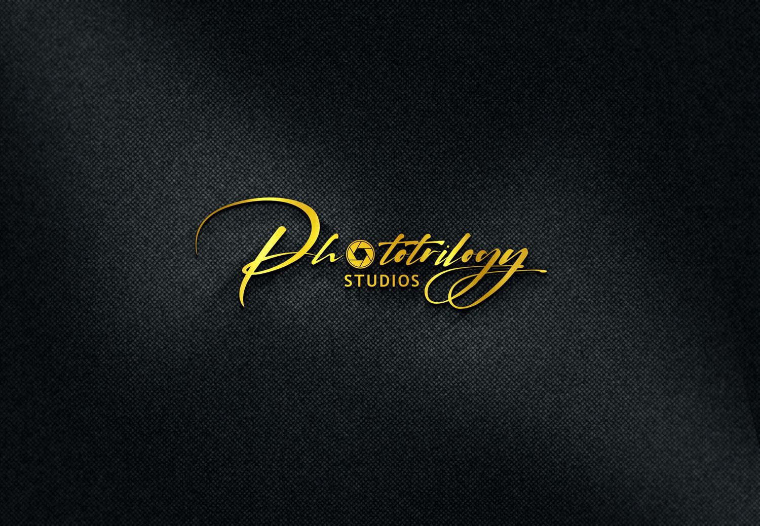 Elegant gold Phototrilogy Studios logo on dark textured fabric background.
