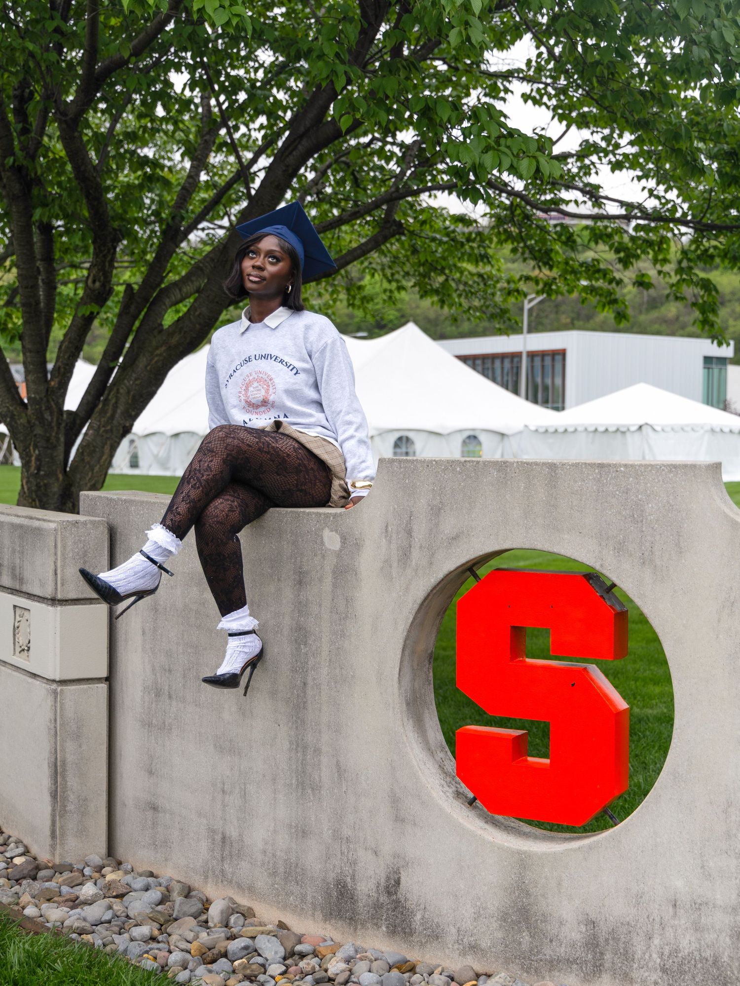 A figure perches on a concrete wall featuring a bold red 'S' emblem, with white event tents visible behind.