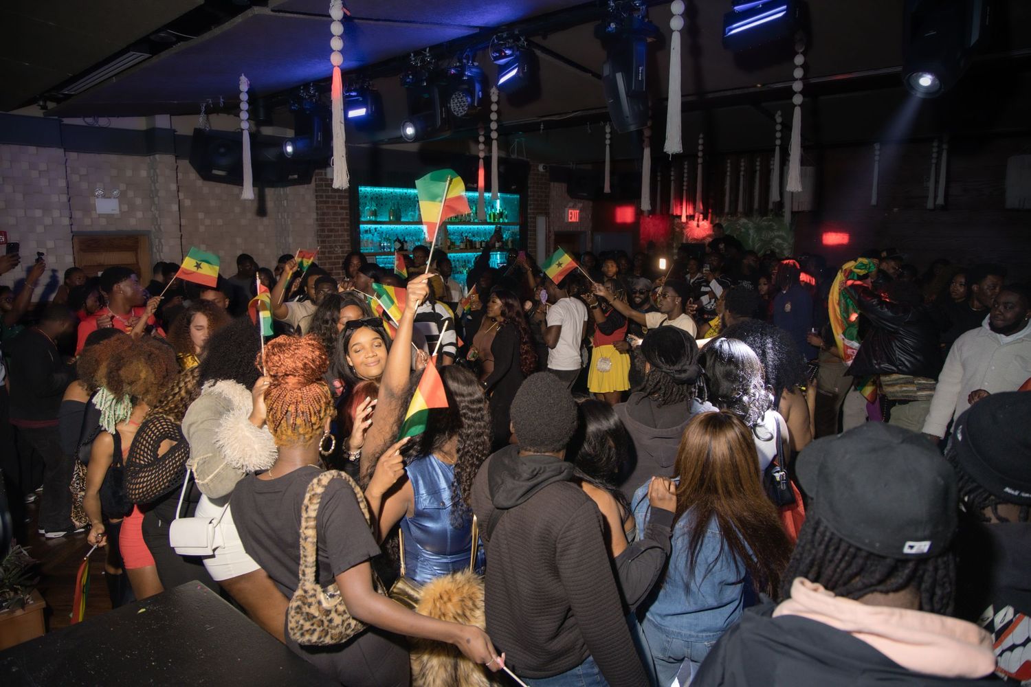 Crowded nightclub scene with dancing people and colorful lighting effects.