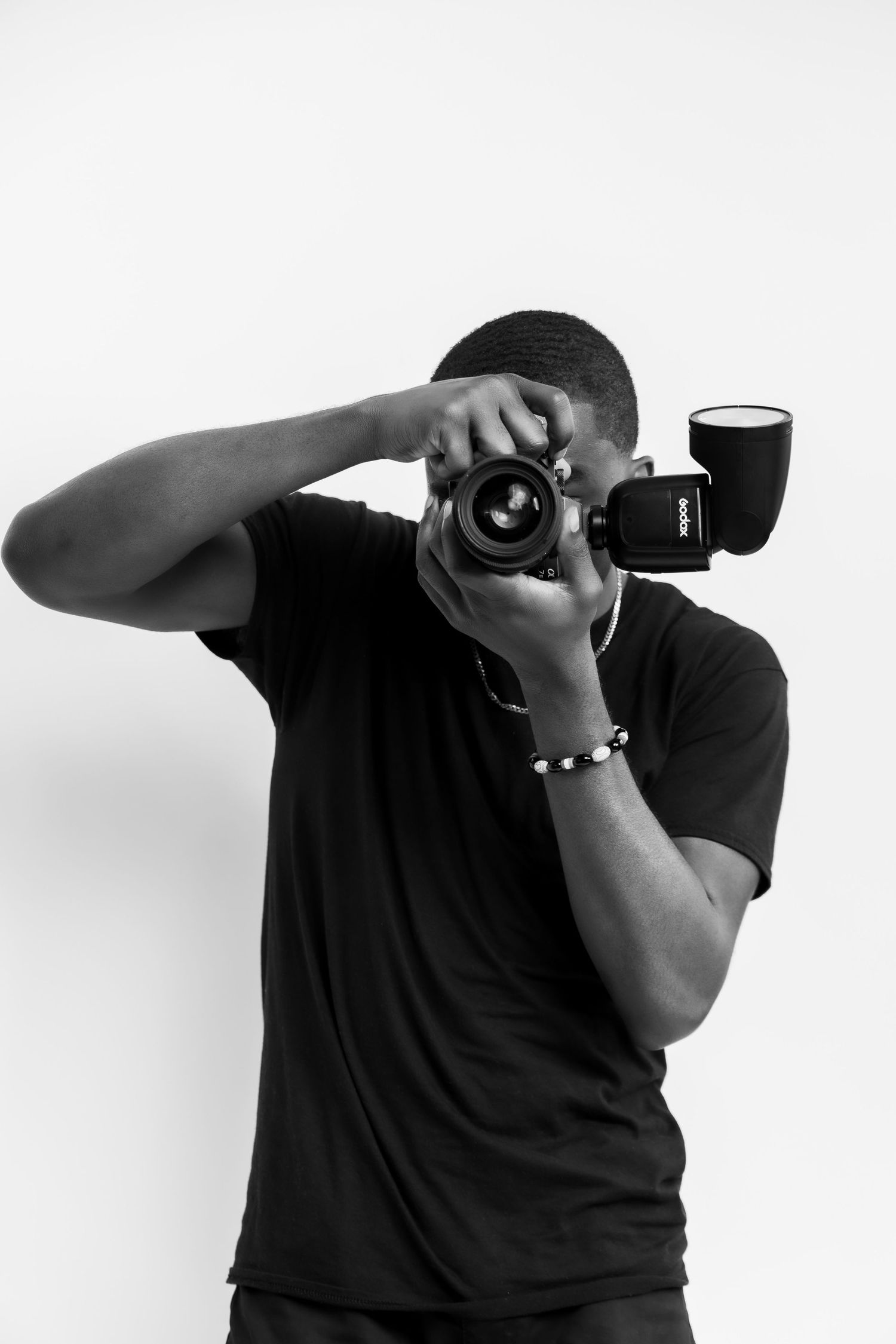 Photographer using professional camera against white background in artistic black and white portrait.