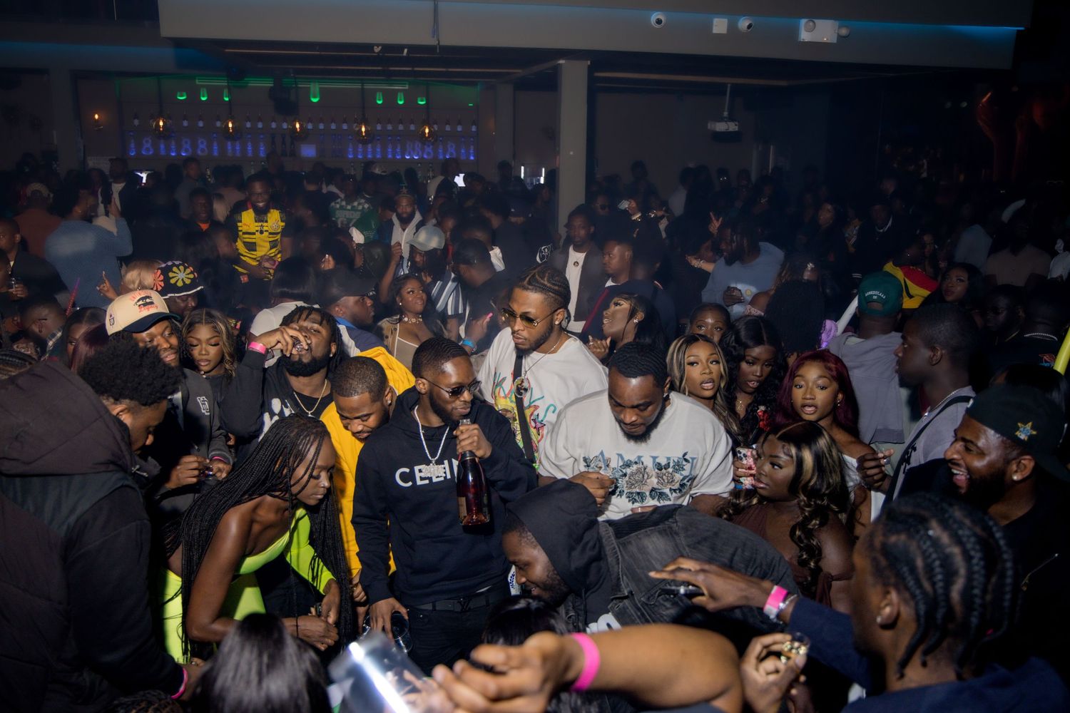 Packed nightclub crowd enjoying a lively party atmosphere with colorful lighting effects.