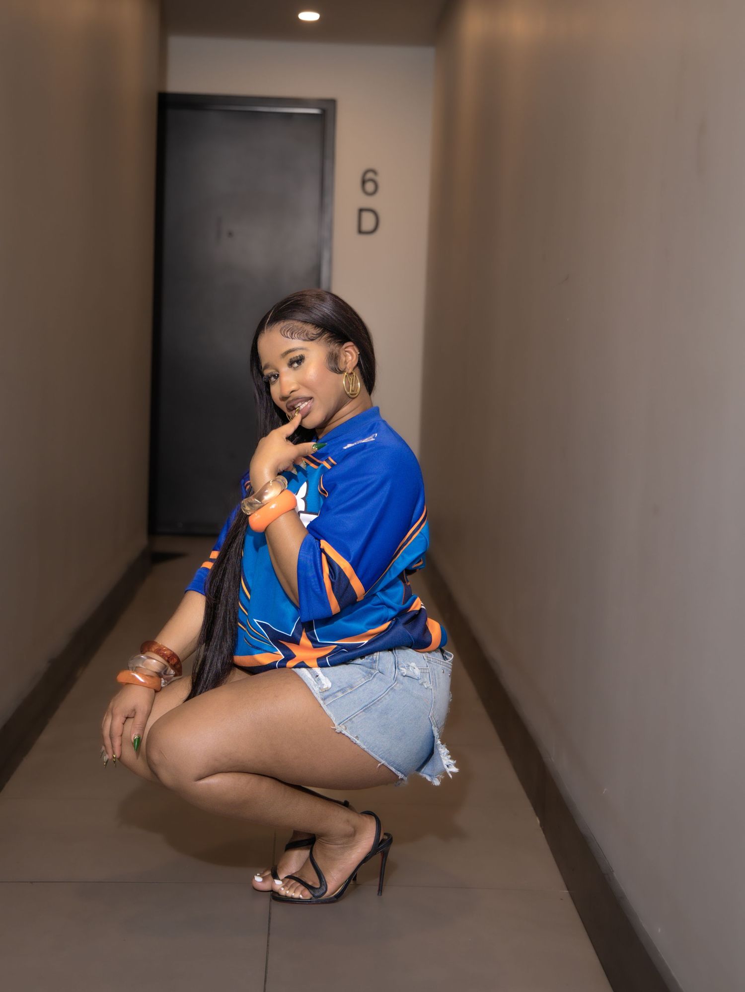 Casual portrait in hallway wearing blue sports jersey and denim shorts.