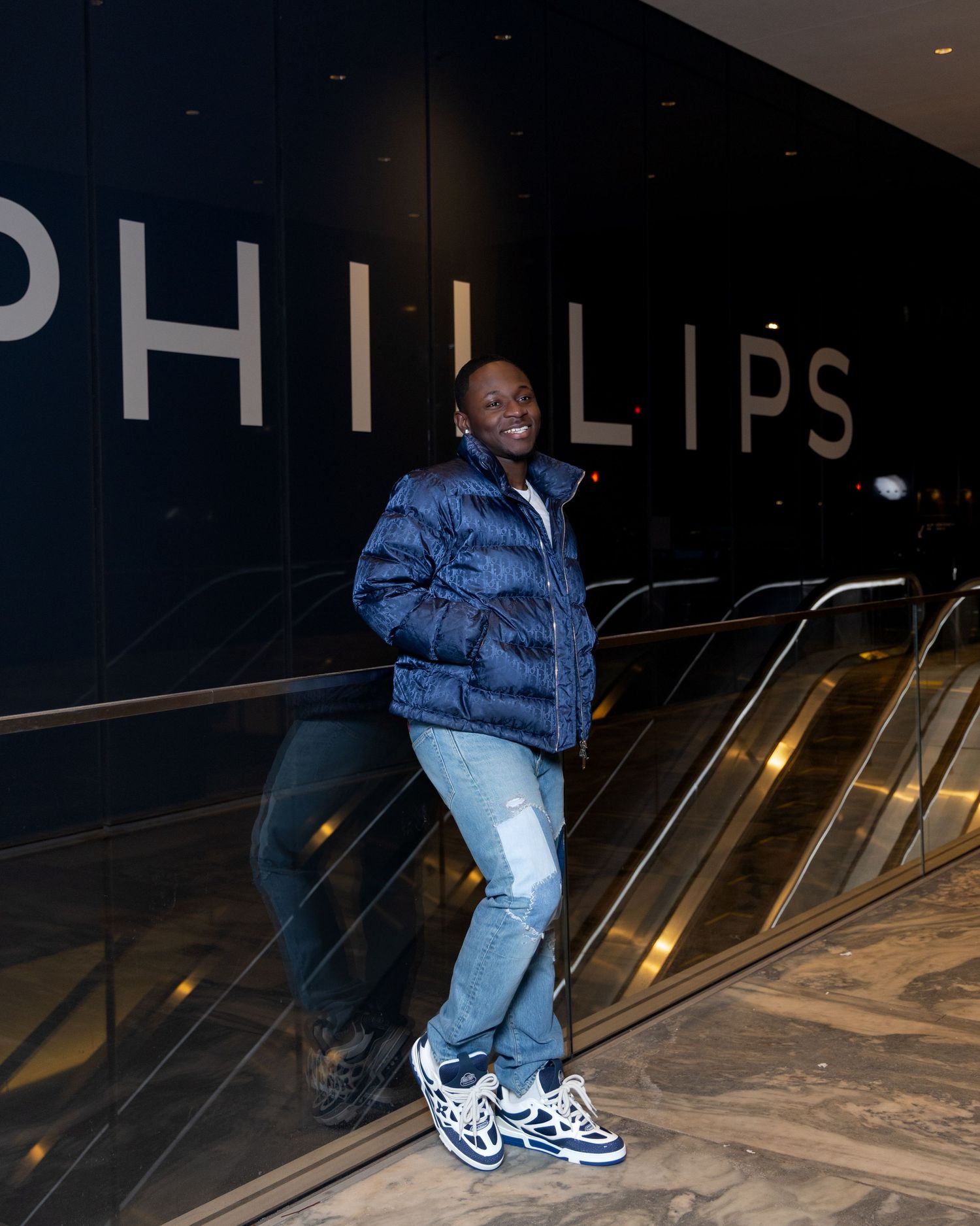 Person in blue puffer jacket and jeans poses on escalator at Phillips.