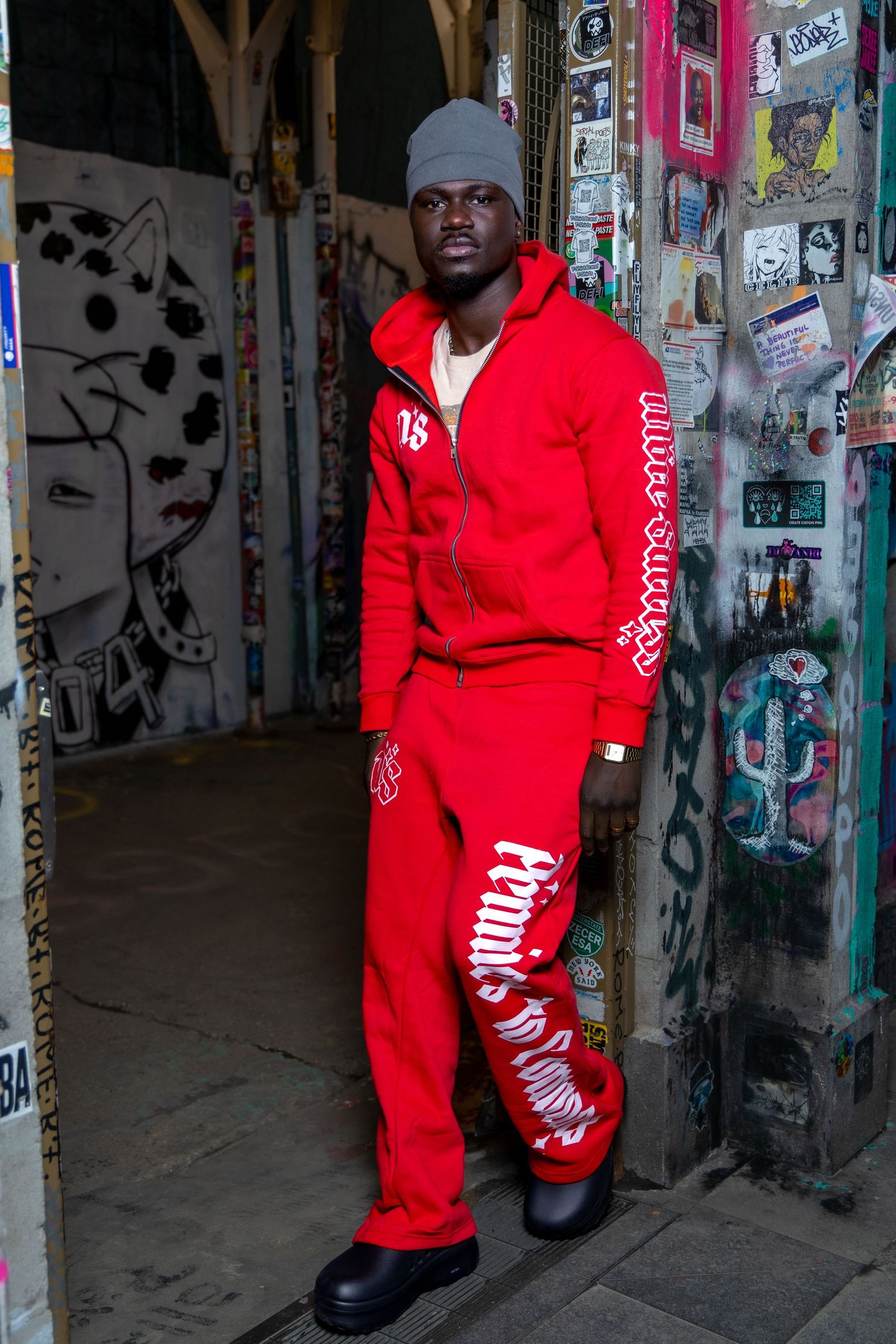 Athletic wear photoshoot featuring bright red tracksuit against graffiti backdrop.