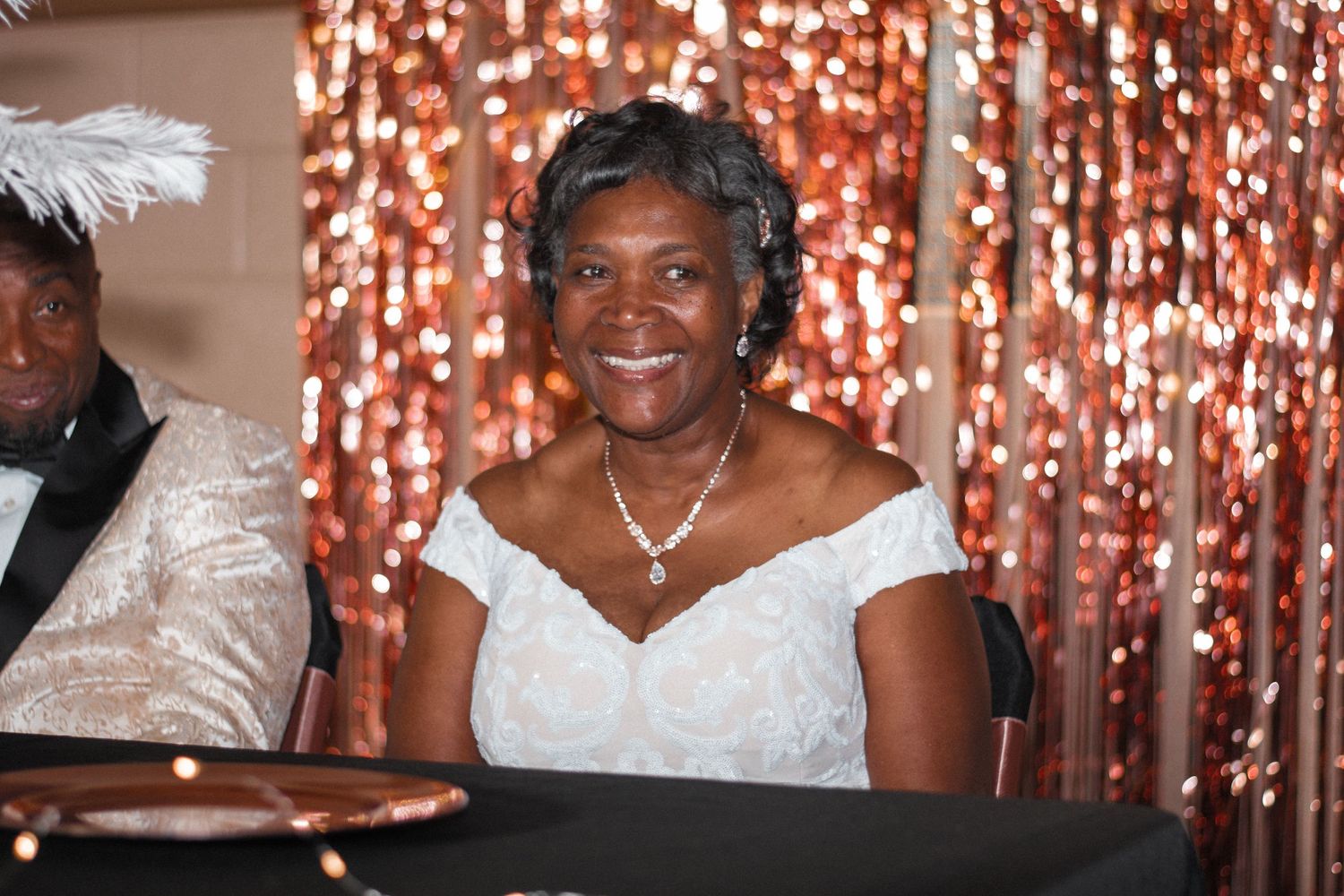 Elegant celebration with sparkly backdrop and formal white attire.