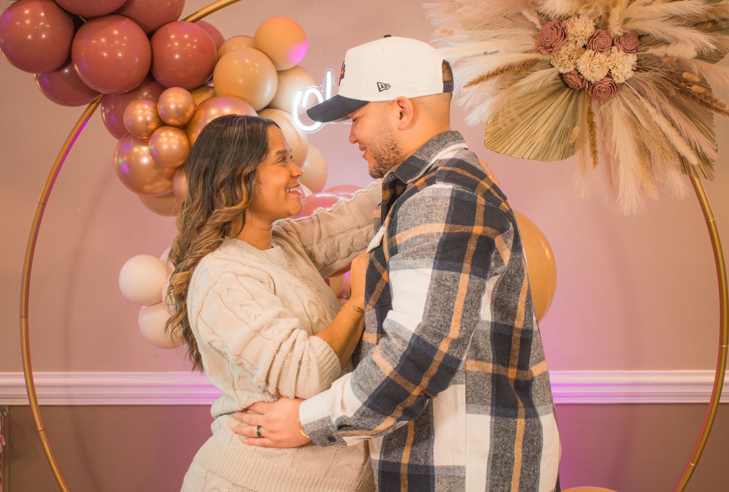 An intimate moment captured between a couple surrounded by balloon decorations in a warm-toned setting.