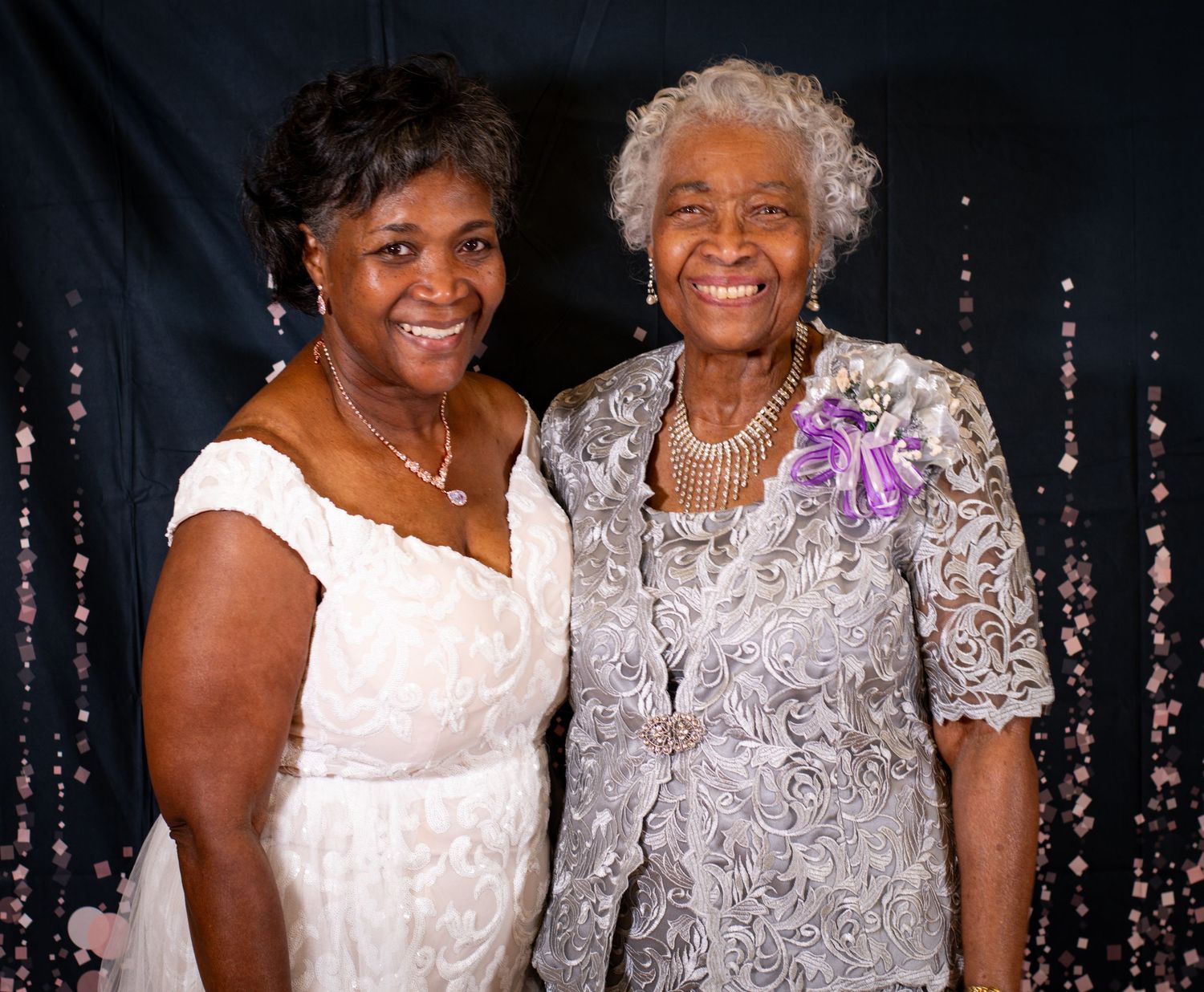 Two women in elegant dresses posing together for a formal portrait.