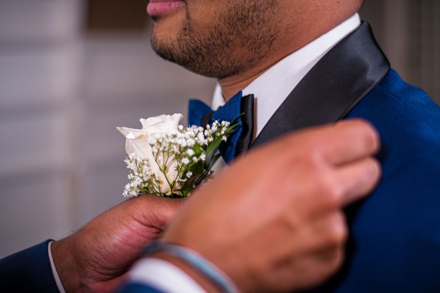 Close-up of boutonniere with baby's breath flowers on navy blue suit jacket.