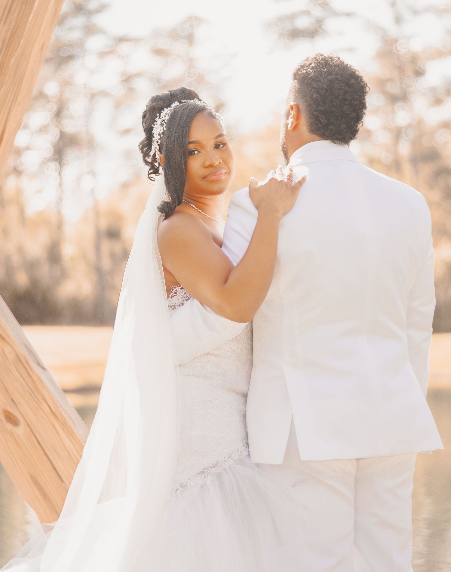 A romantic wedding couple in white attire sharing an intimate moment during their outdoor photo session.