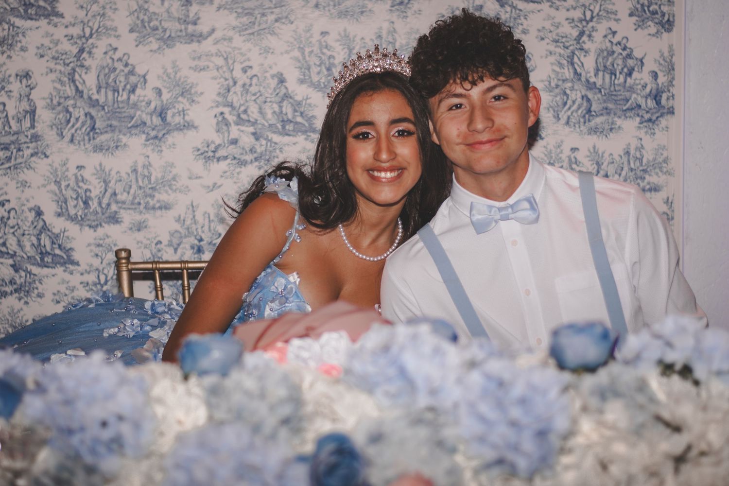 Formal celebration portrait against blue toile wallpaper with floral decorations.