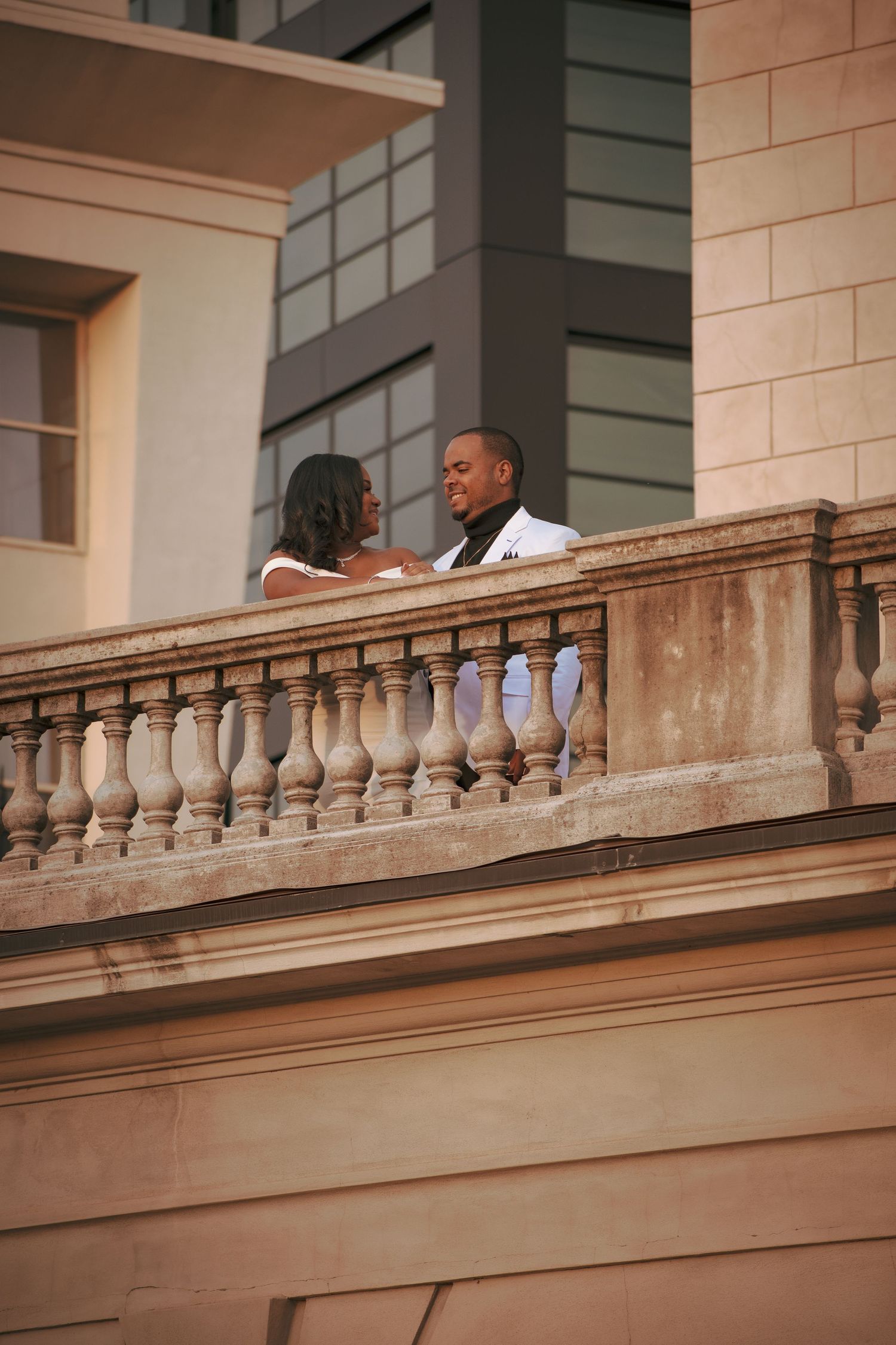 Couple sharing an intimate moment on a vintage balcony with stone balusters.