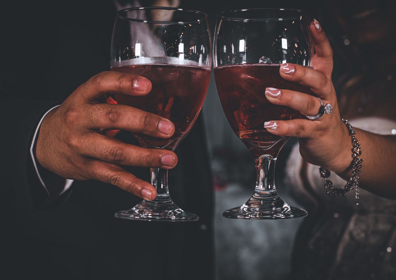 Two wine glasses clink together in a celebratory toast against dark background.