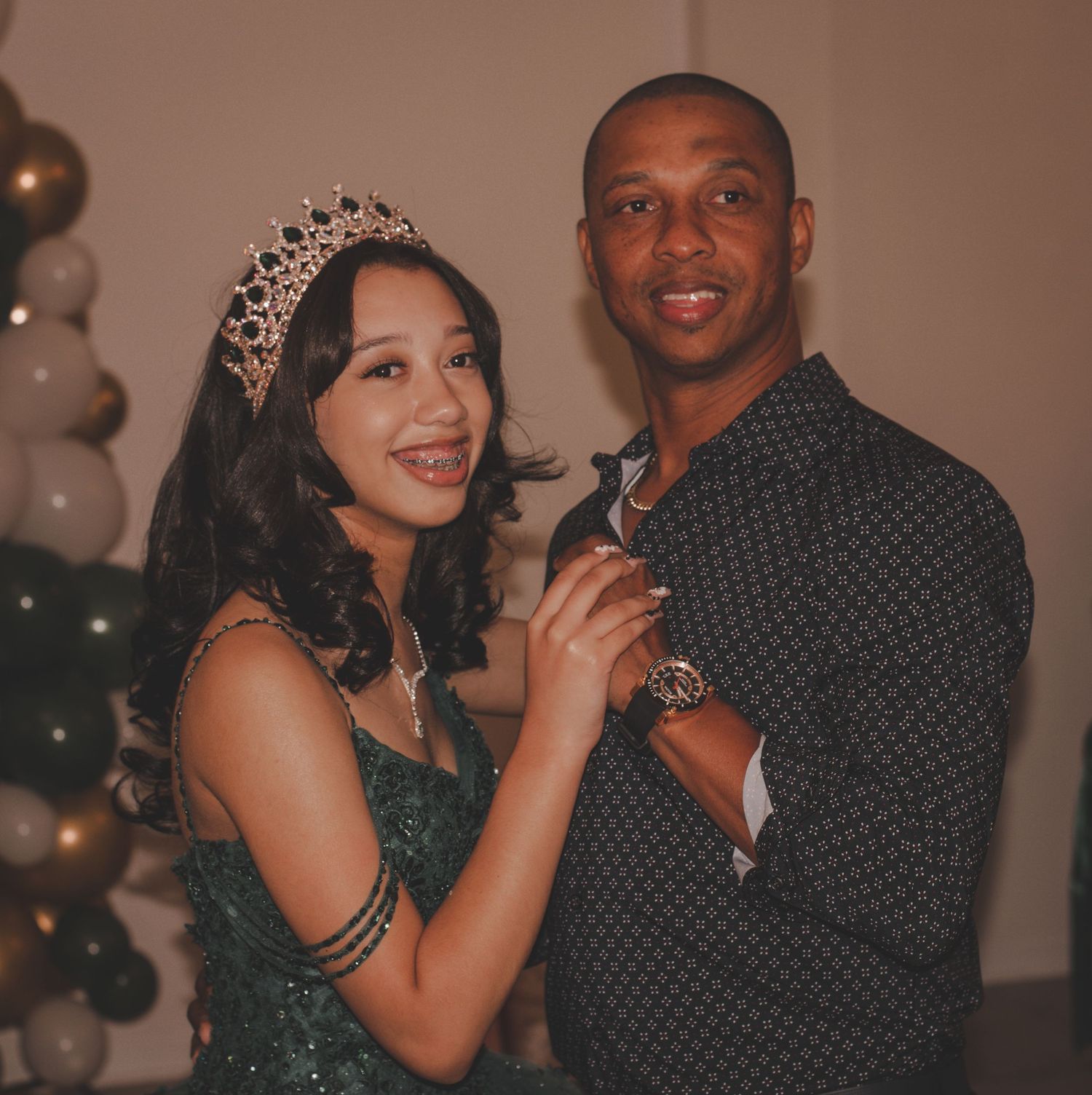 Quinceañera celebration with emerald green dress, tiara and festive balloon decorations.