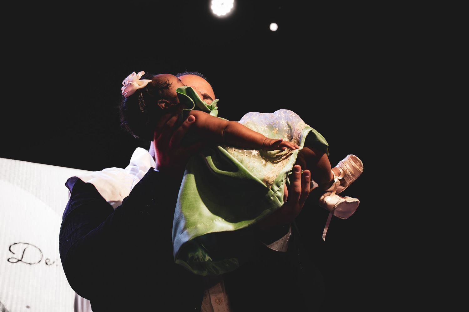 A couple performs an elegant ballroom dance lift on a dimly lit stage during a dance competition.