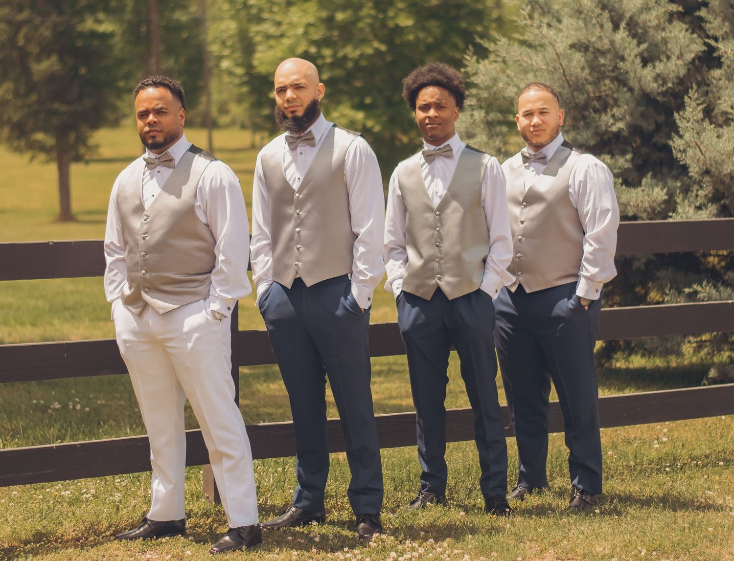 Group of groomsmen in navy and white attire sitting casually on steps outdoors in a park setting.