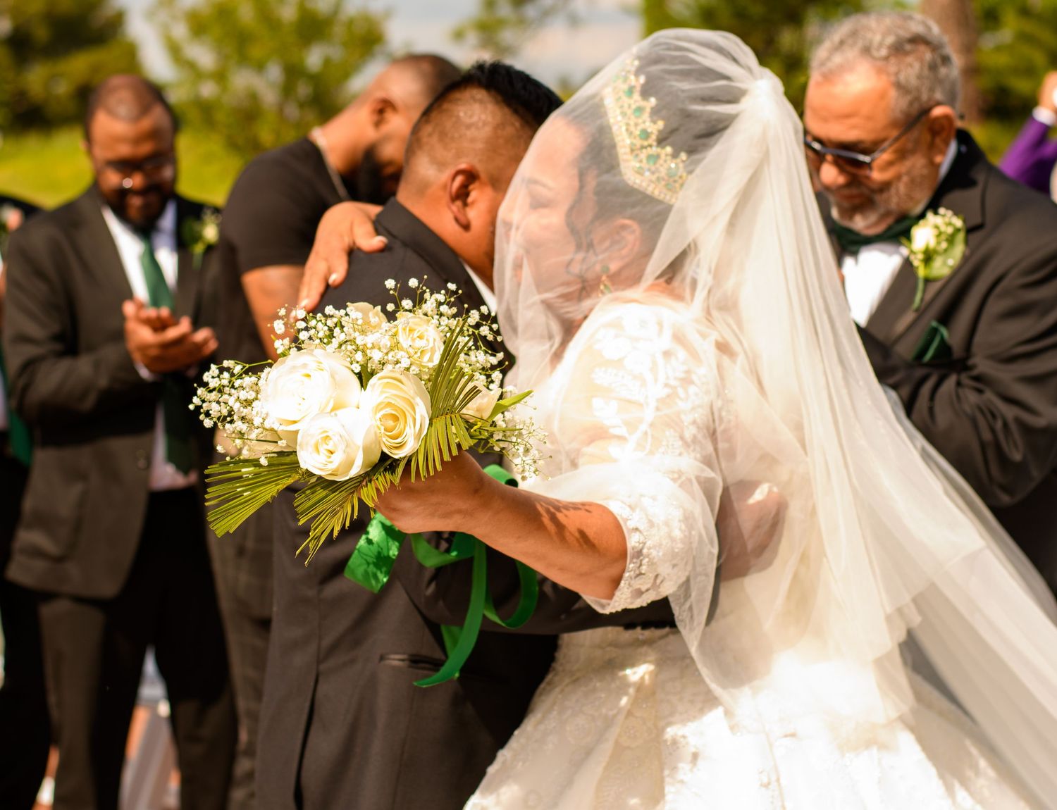 A joyous wedding ceremony moment with a couple sharing a kiss while holding white floral bouquet.