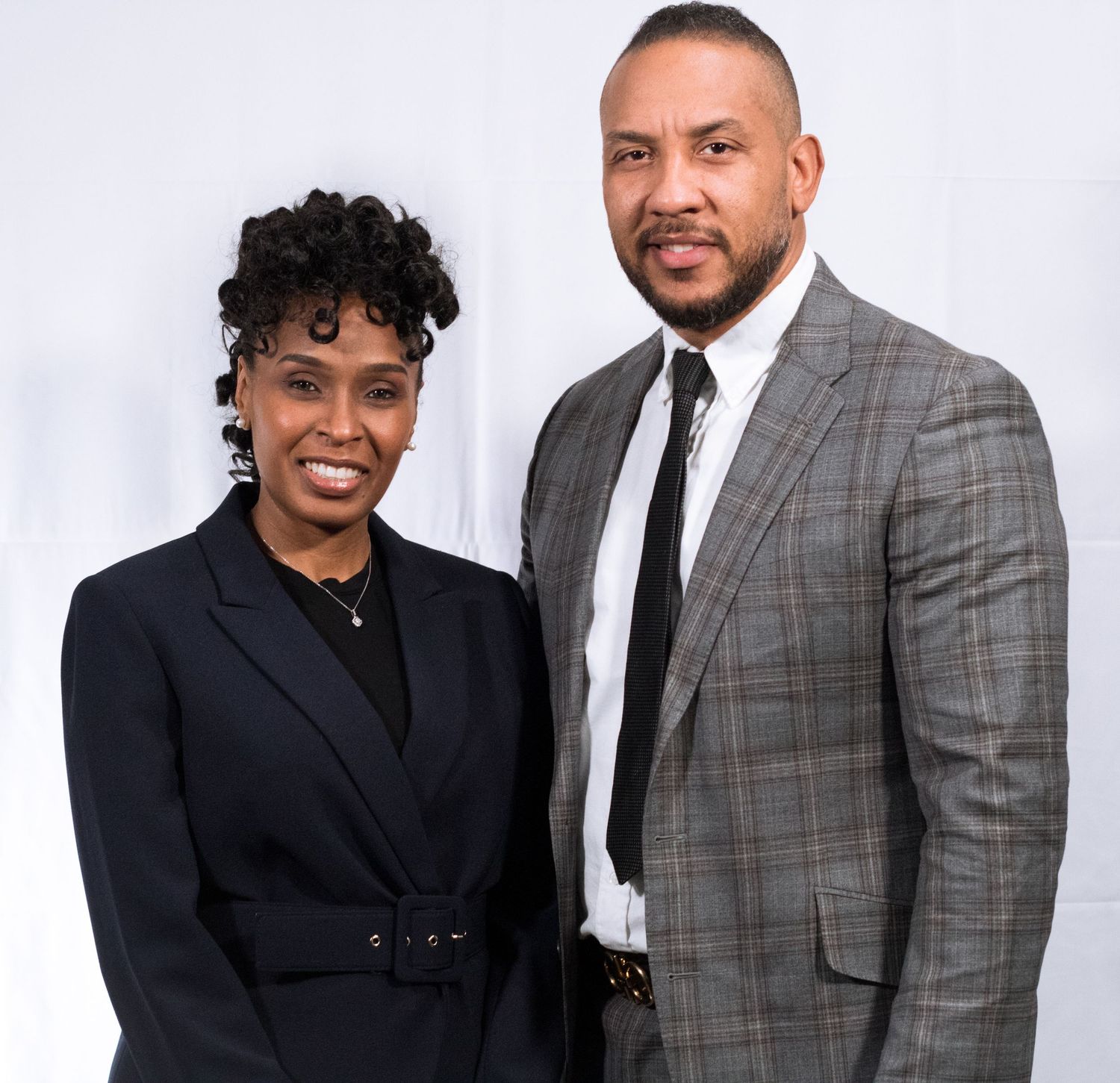 Formal studio portrait of two people in business attire against white backdrop.
