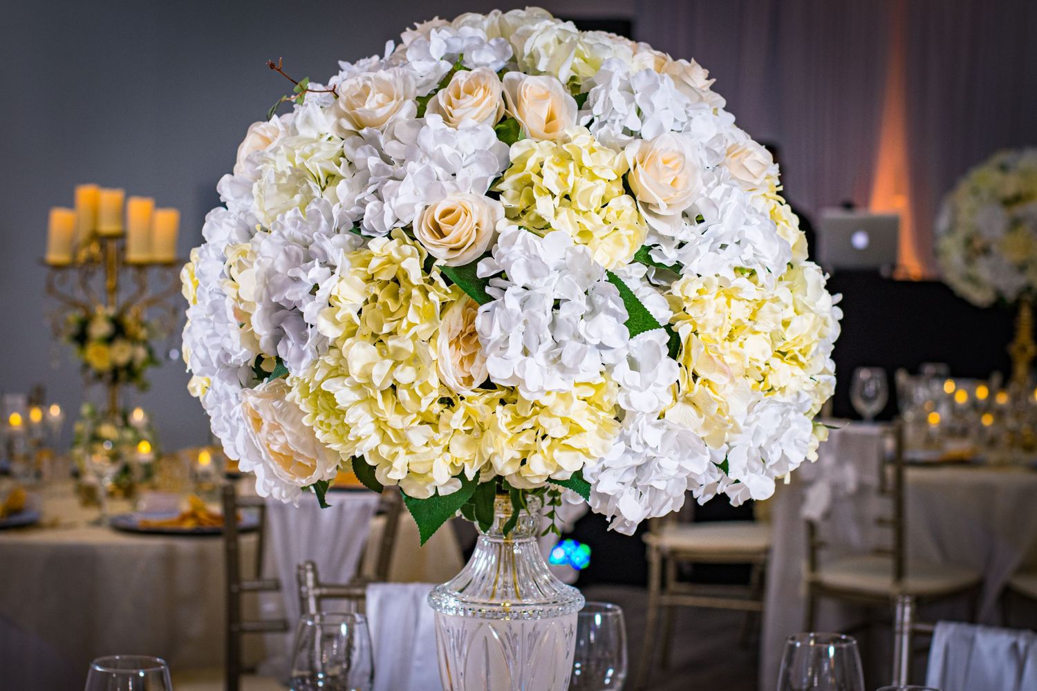 Luxurious white and yellow hydrangea centerpiece arrangement in crystal vase.