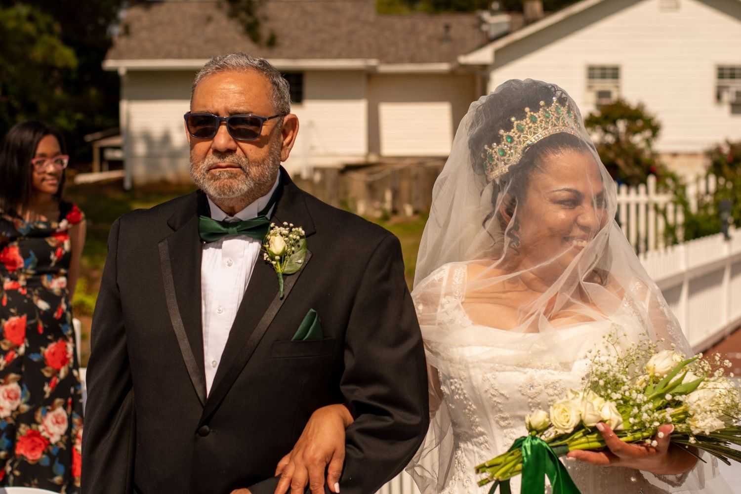 Wedding processional moment outdoors with classic formal attire and white veil.