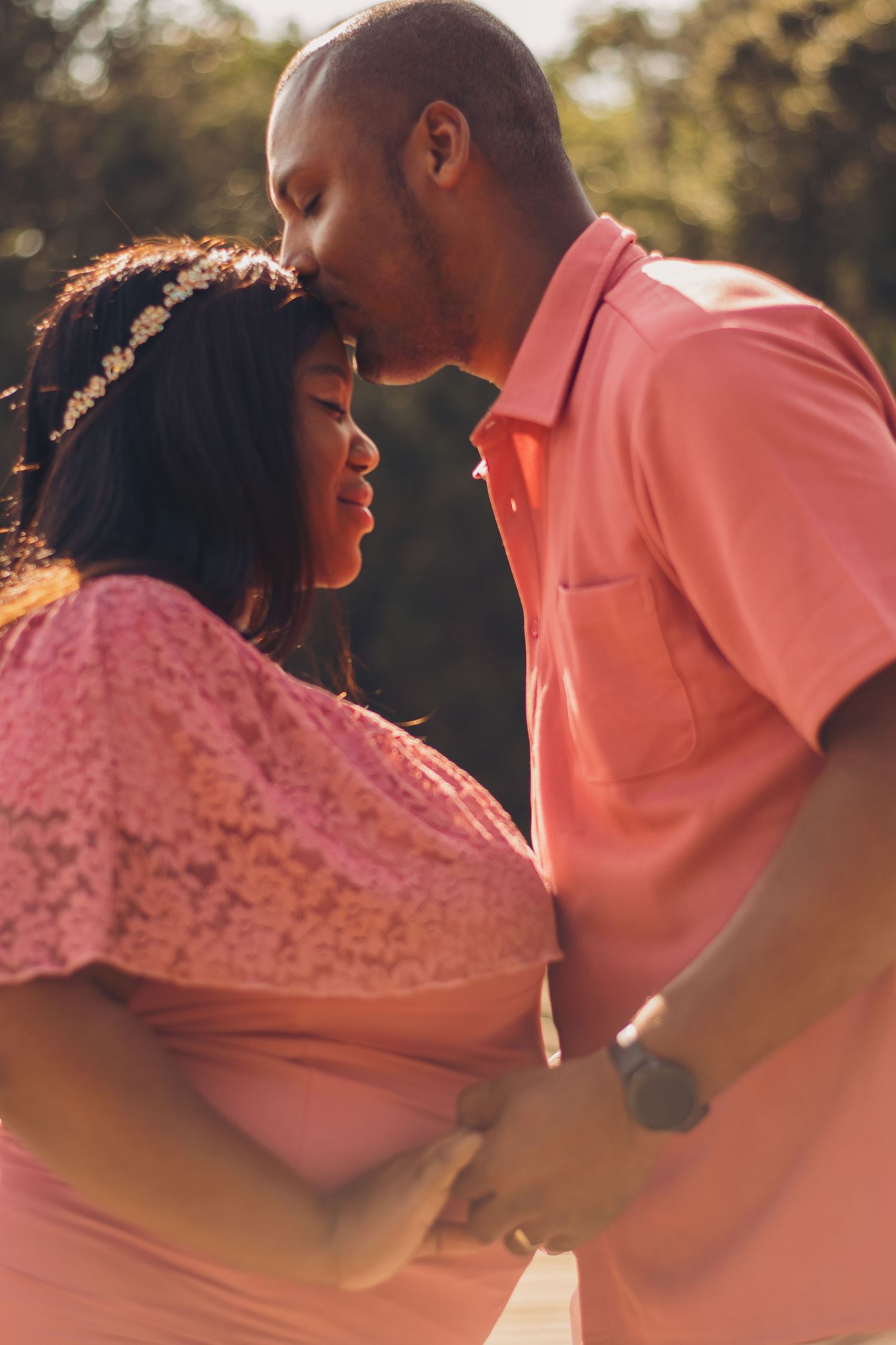 Intimate moment between couple during sunset maternity photoshoot.