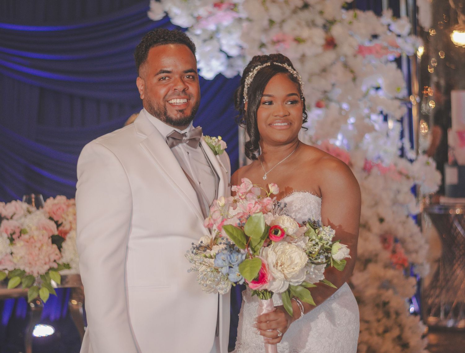 Elegant wedding ceremony with pink floral decor and blue lighting creates a romantic atmosphere for the happy couple.