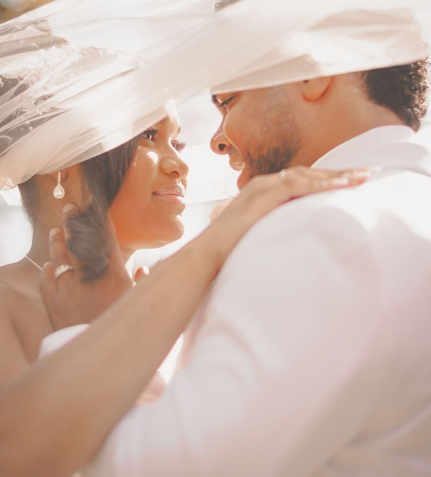 A tender wedding moment captured in soft lighting as the couple shares an intimate close-up embrace.