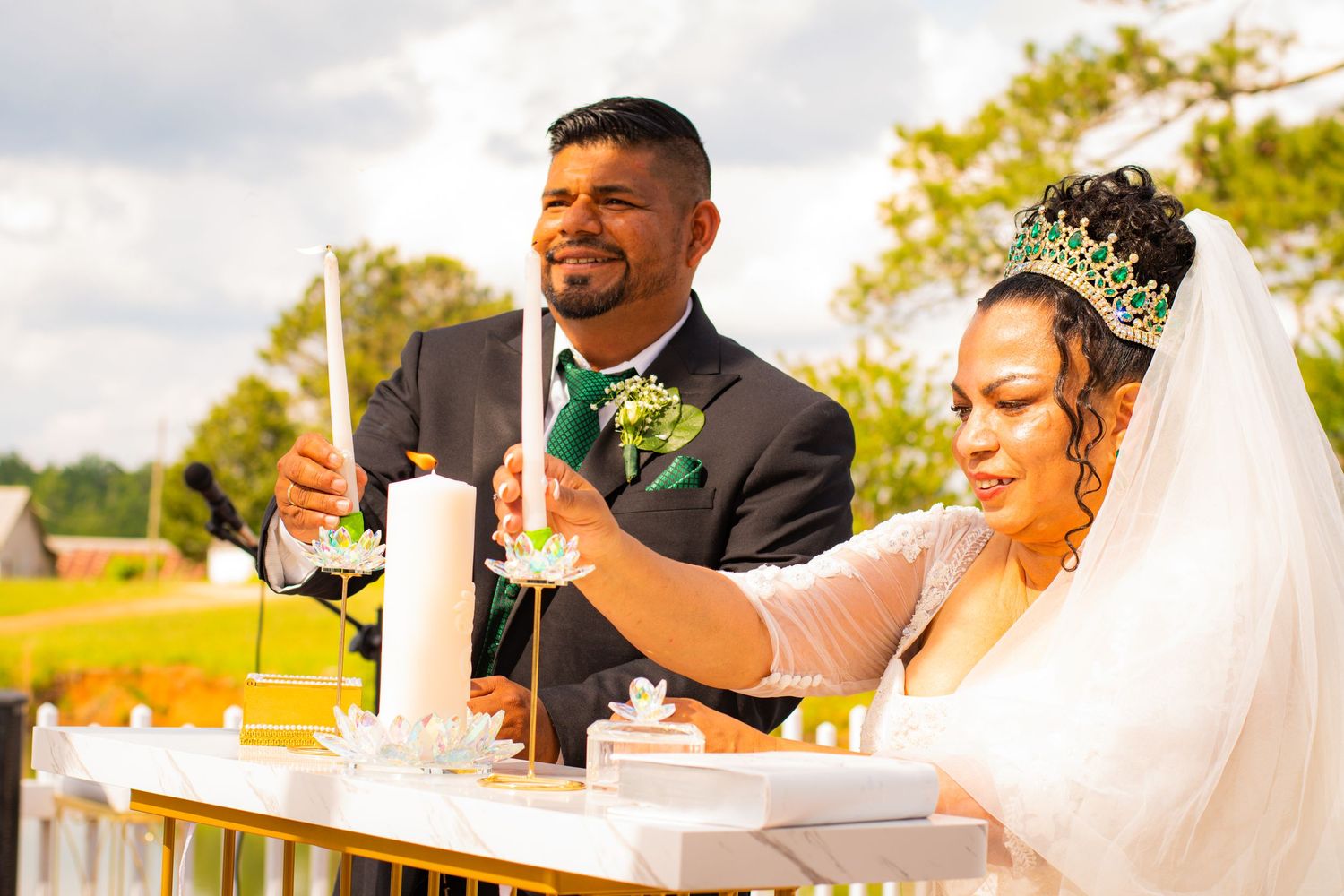 Newlyweds perform a unity candle ceremony at their outdoor wedding reception.