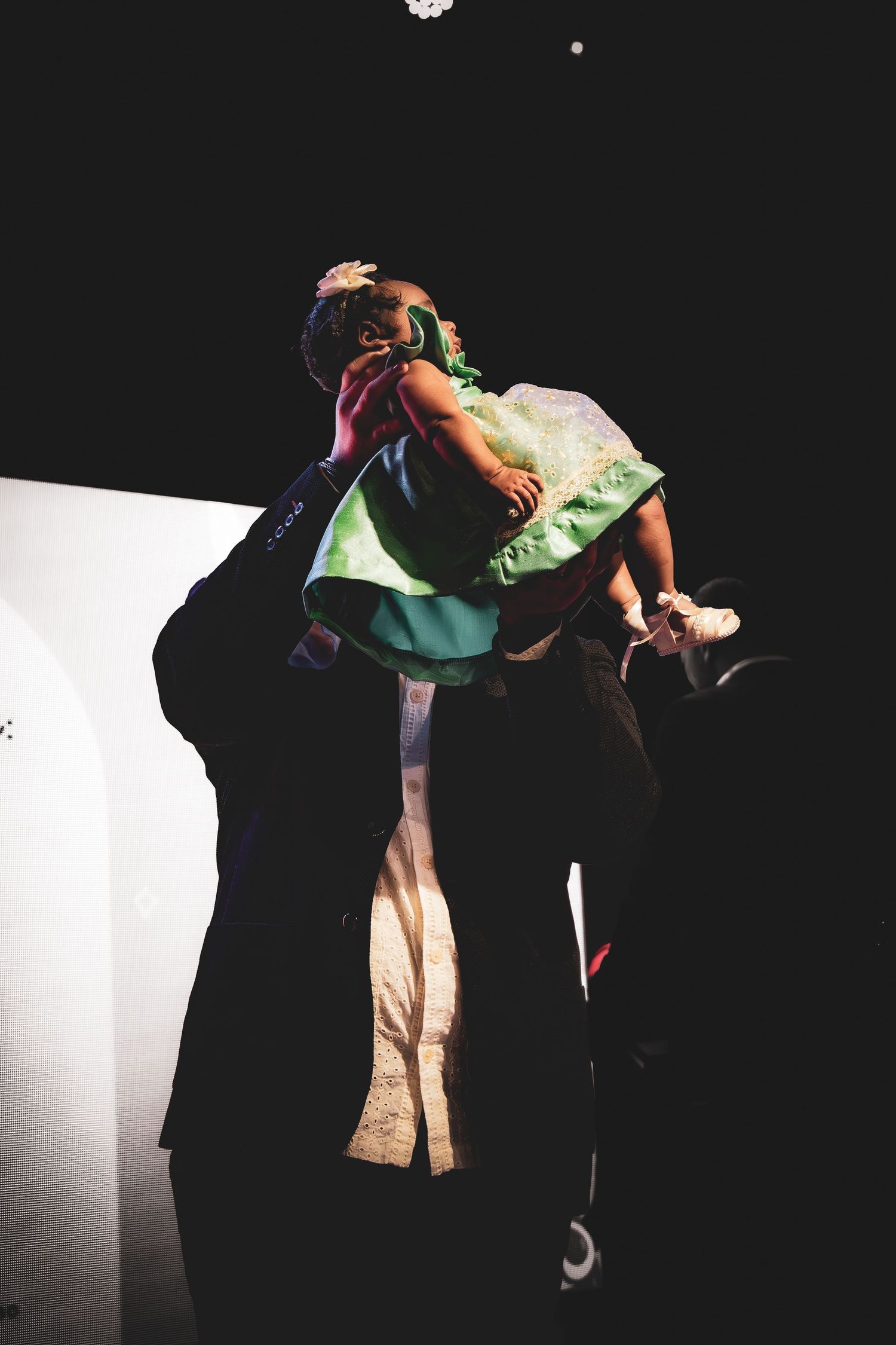 Dramatic performance on stage with dancer in flowing green dress making expressive movements against dark backdrop.