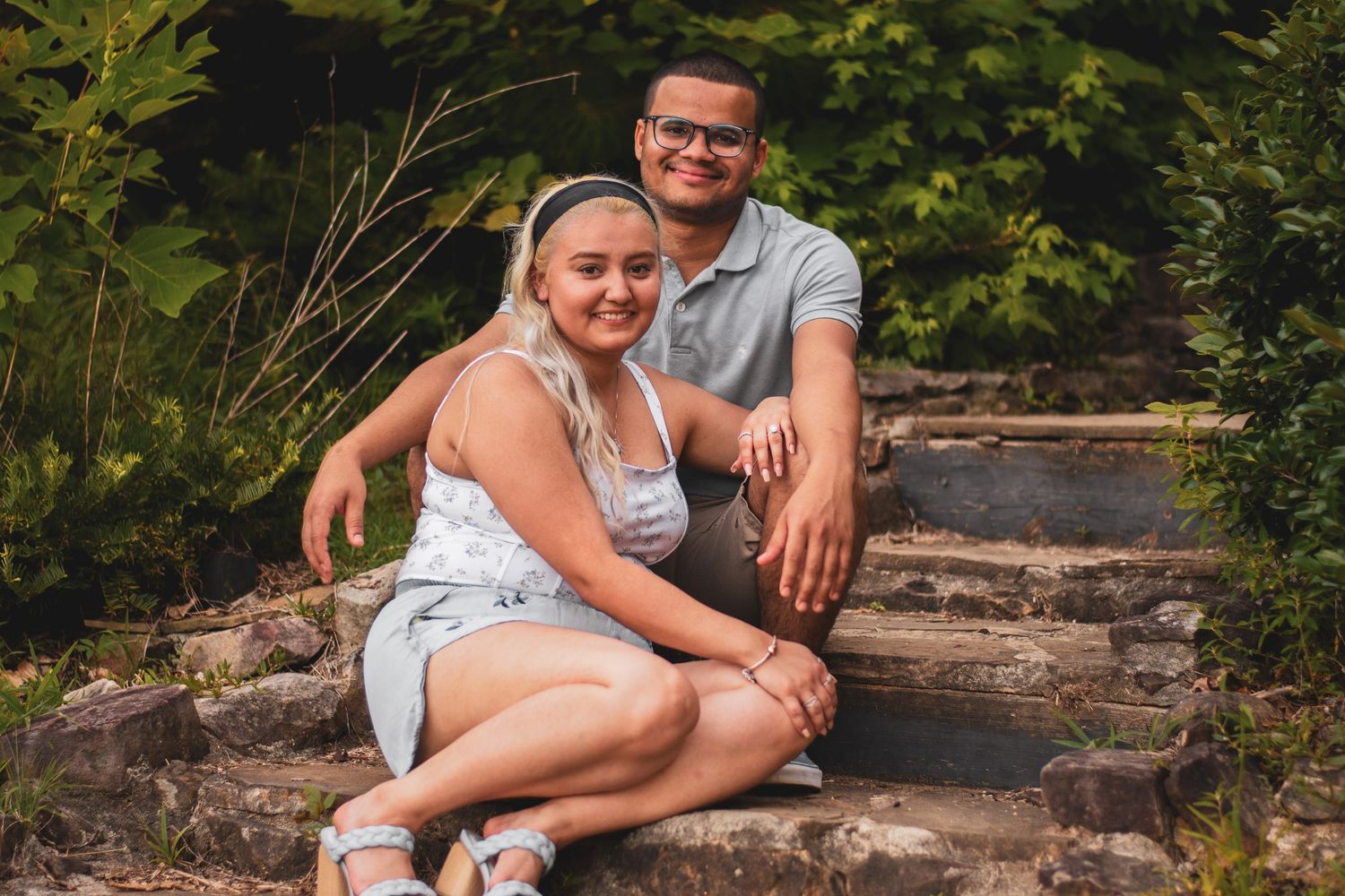 A couple relaxes together on rustic wooden logs in a natural outdoor setting.