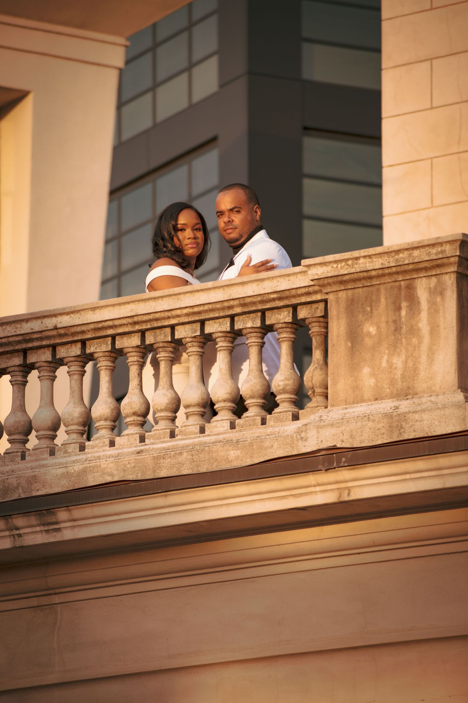 Couple sharing intimate moment on classical architecture balcony at sunset.