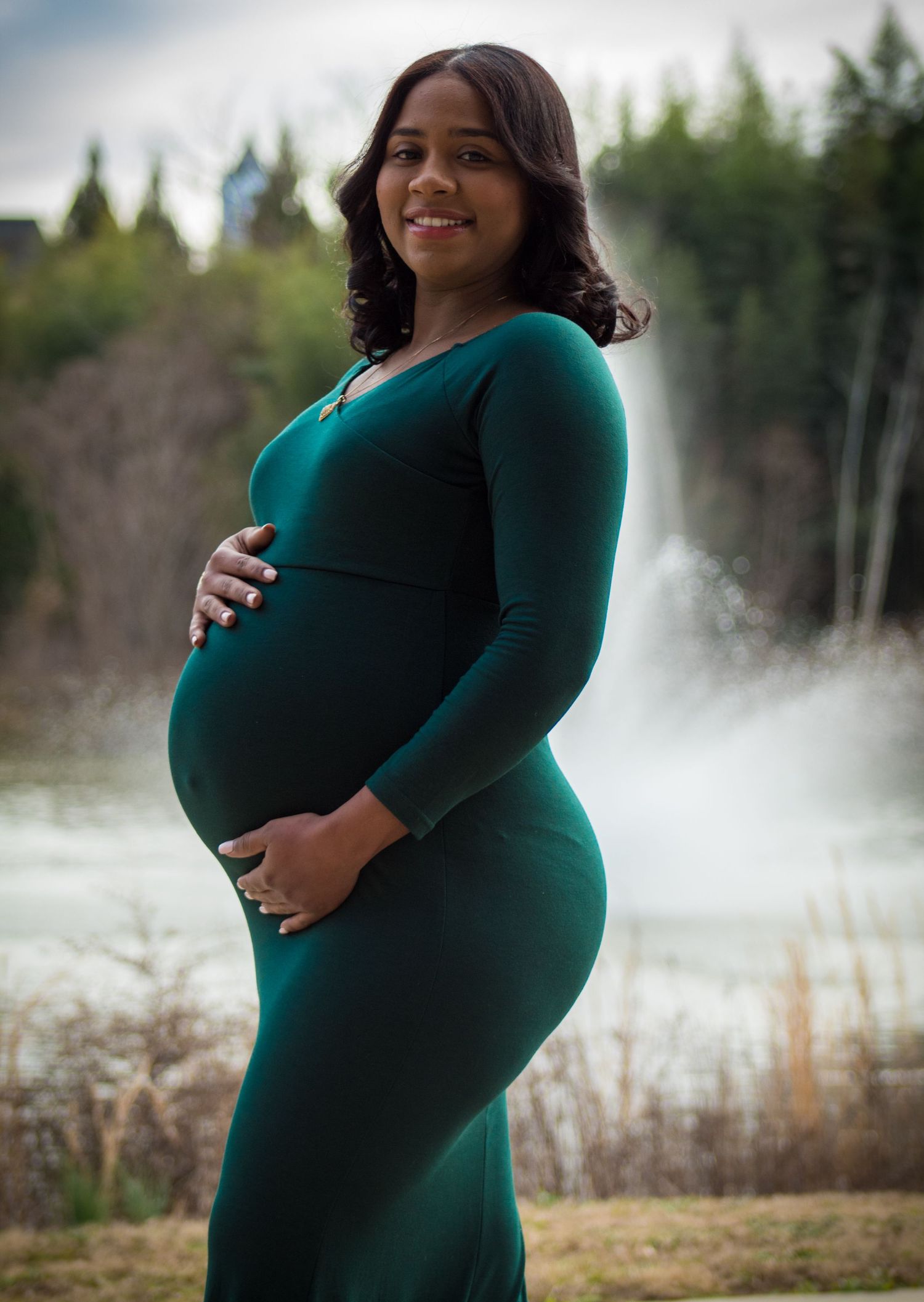 Joyful maternity portrait in forest setting with misty background.