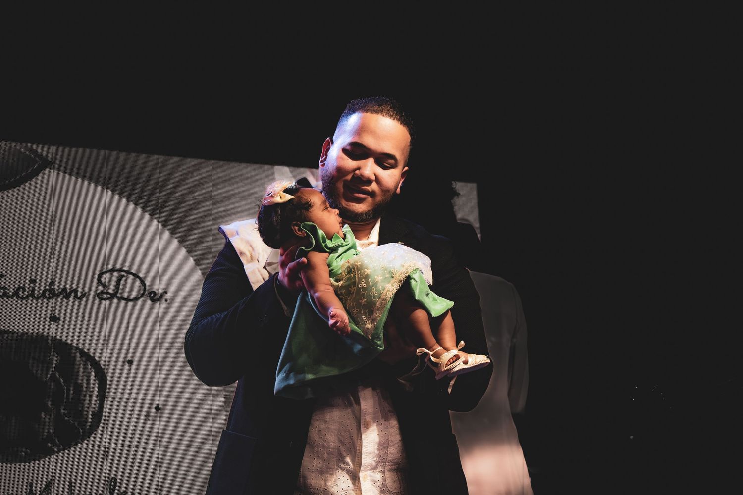 Stage performer holding microphone and gesturing energetically during live performance.