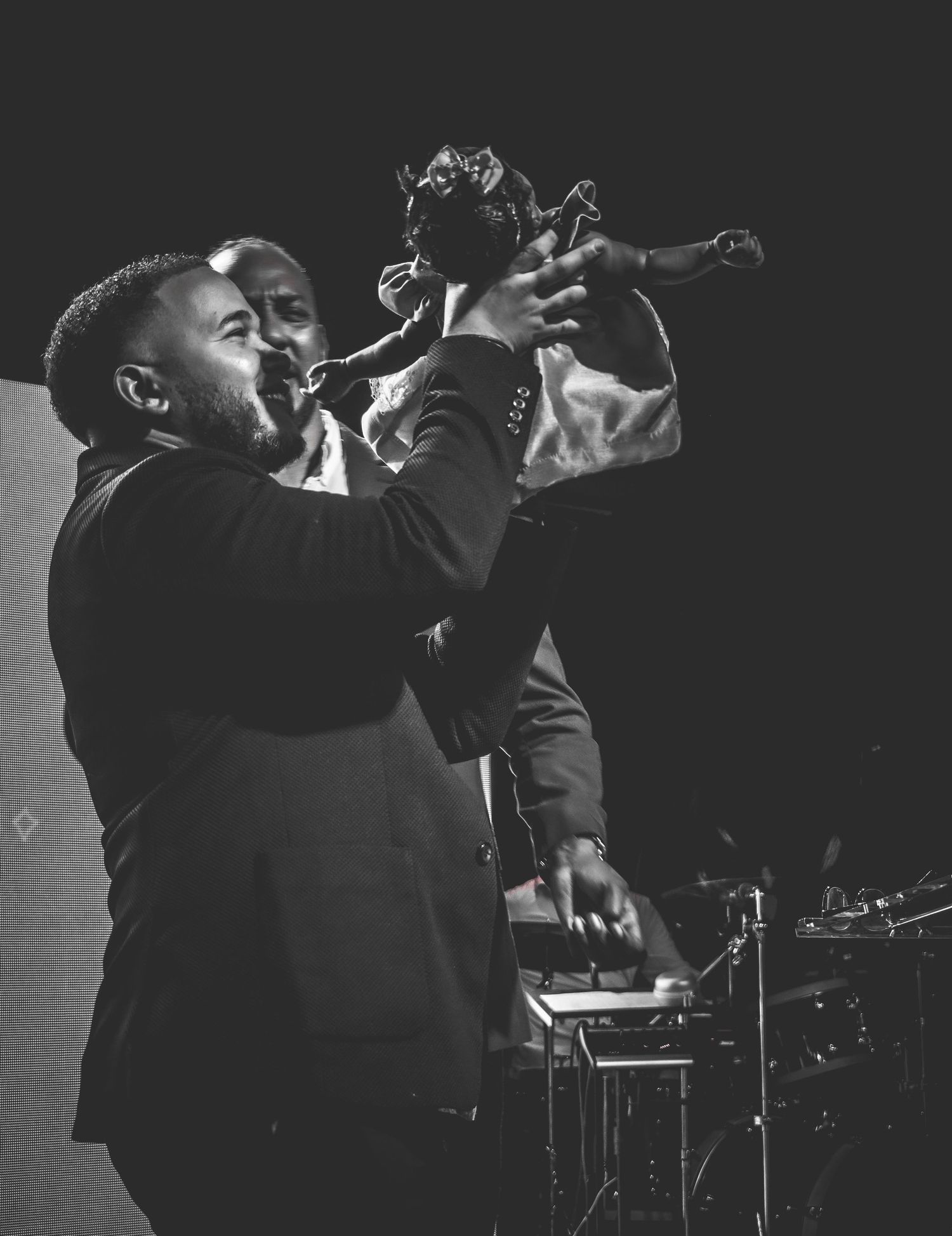 Black and white photo of an energetic performer singing passionately into a microphone on stage.