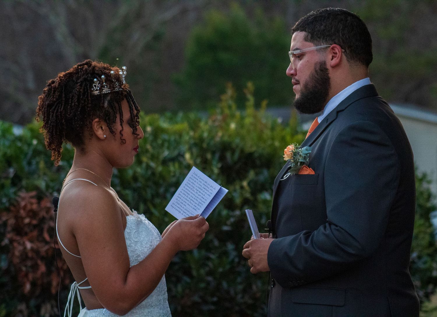 A couple exchanges vows during their outdoor wedding ceremony at sunset.