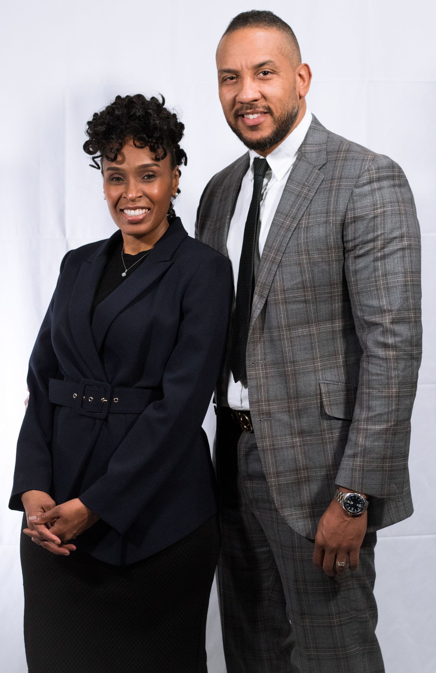 Professional business portrait of two people in formal attire against white background.