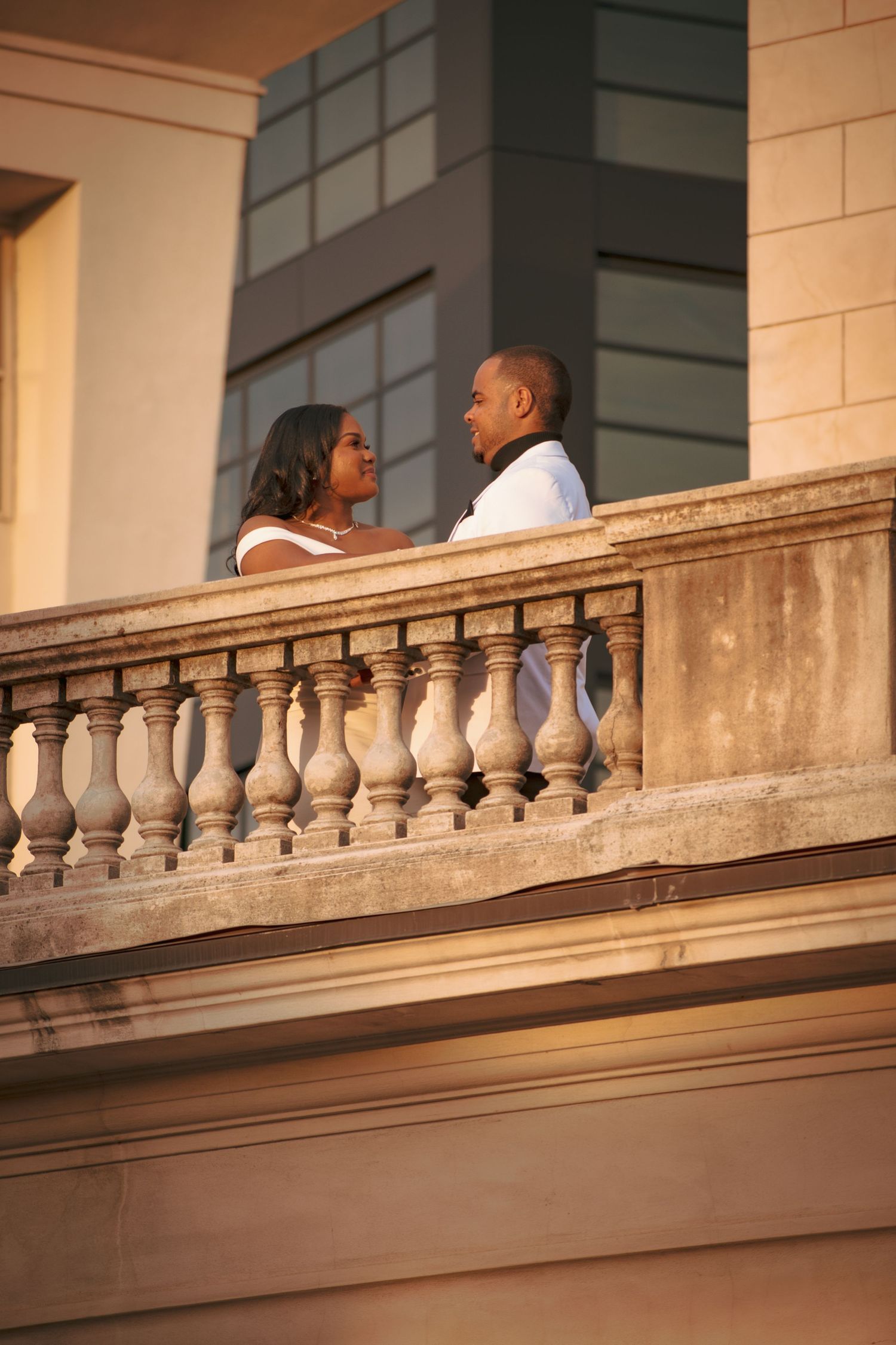 Romantic sunset portrait of couple on historic balcony with stone balusters.