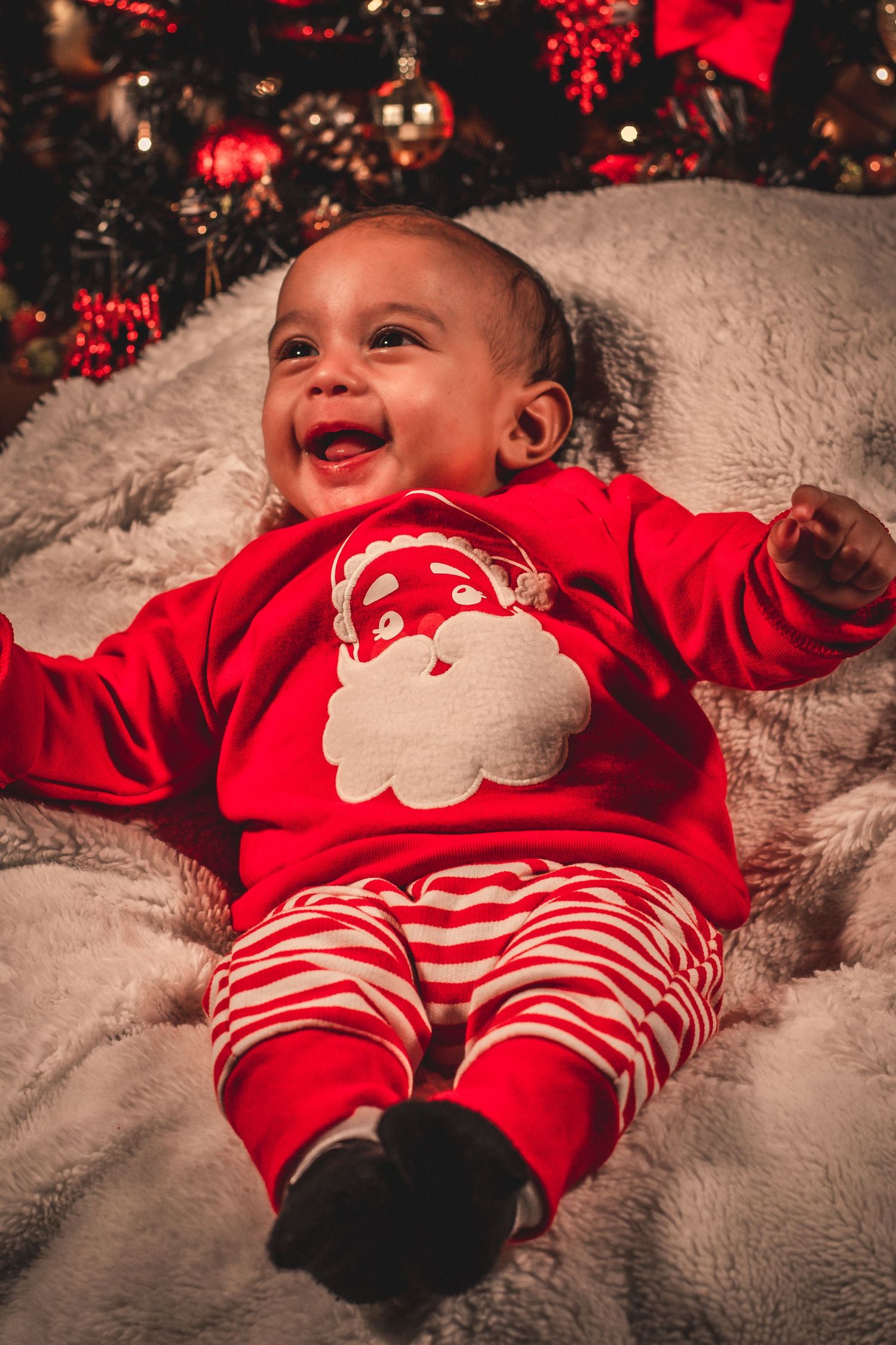 Joyful holiday moment captured in front of a decorated Christmas tree with festive red attire.