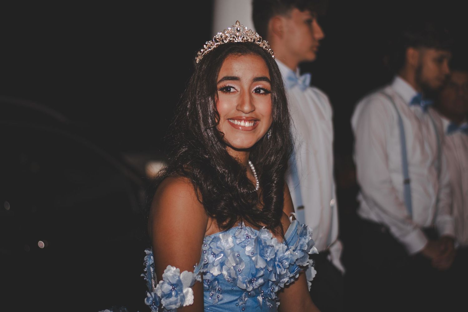 Elegant celebration featuring sparkly blue gown and tiara in evening setting.