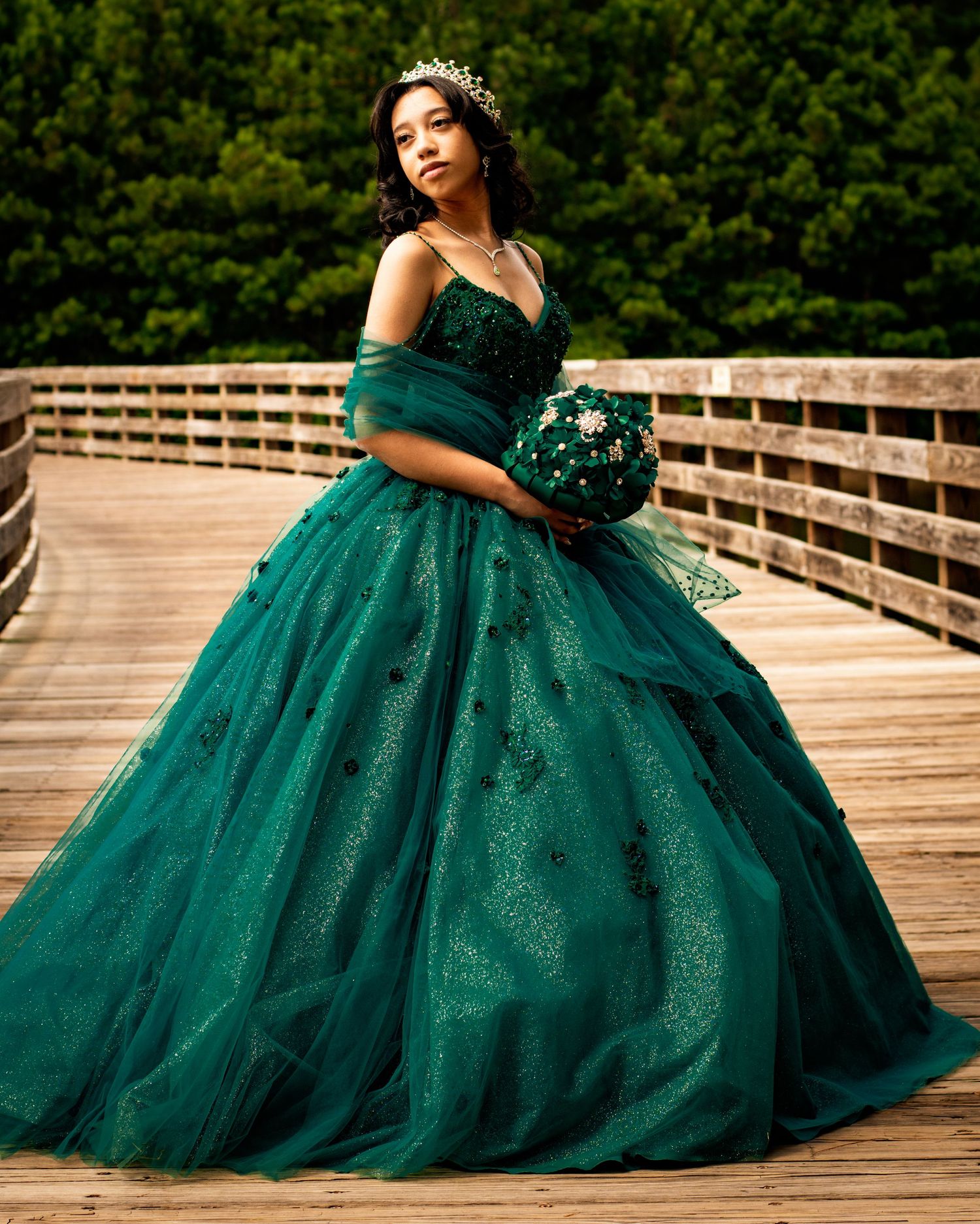 An elegant portrait featuring a sparkling emerald green ball gown and crystal tiara.